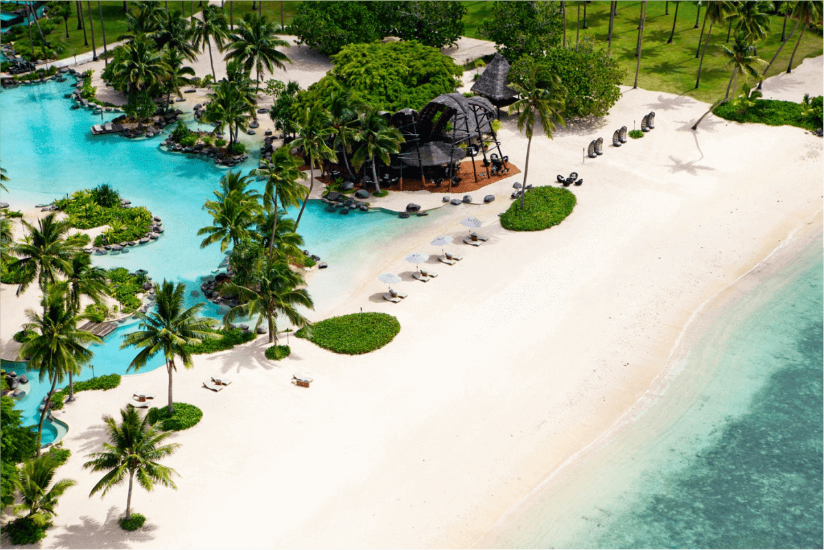 Aerial view of a tropical island resort with white sand beach, palm trees, and lagoon pools, the kind of property photography that wins over vacation travelers
