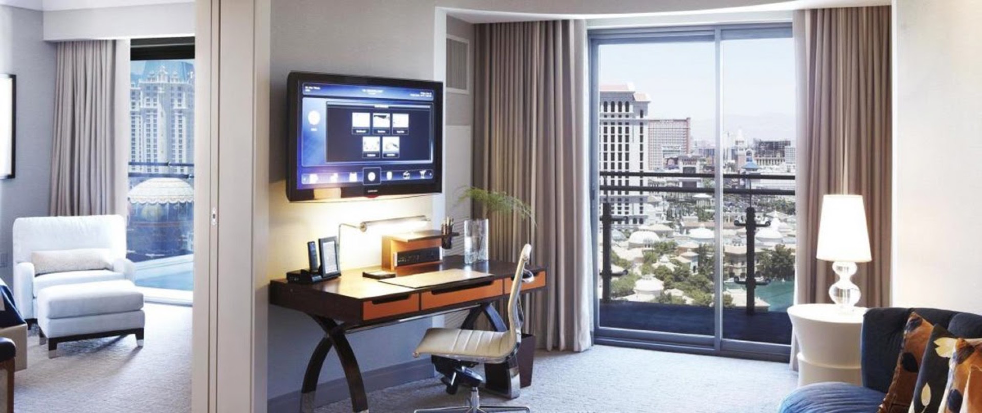 Cosmopolitan Las Vegas hotel room with wall-mounted TV, work desk, and floor-to-ceiling windows overlooking the Strip