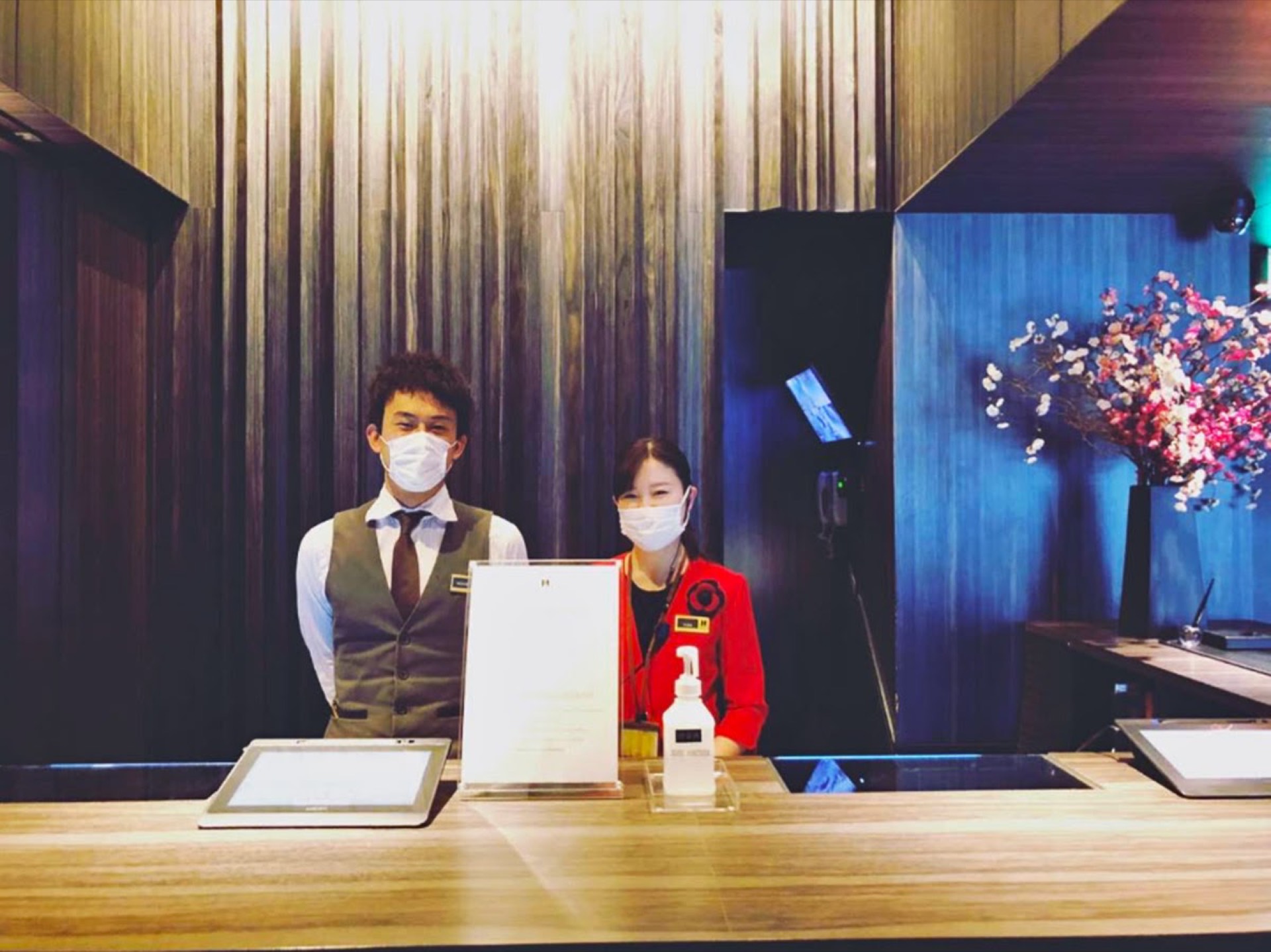 Hotel and Residence Roppongi Tokyo front desk staff wearing masks behind a sanitizer station, showcasing safety measures