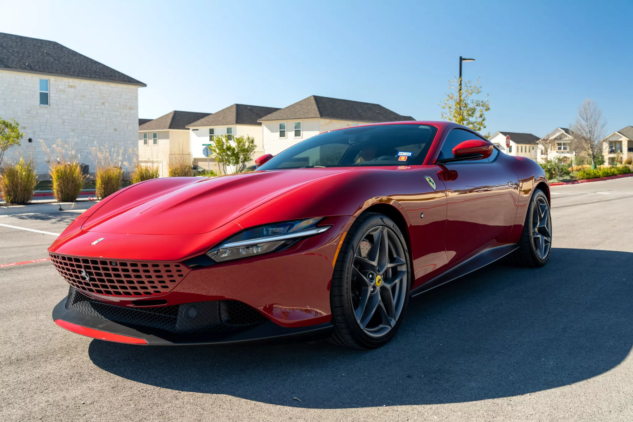 Red Ferrari Roma auto photography in a sunlit residential neighborhood, three-quarter front view