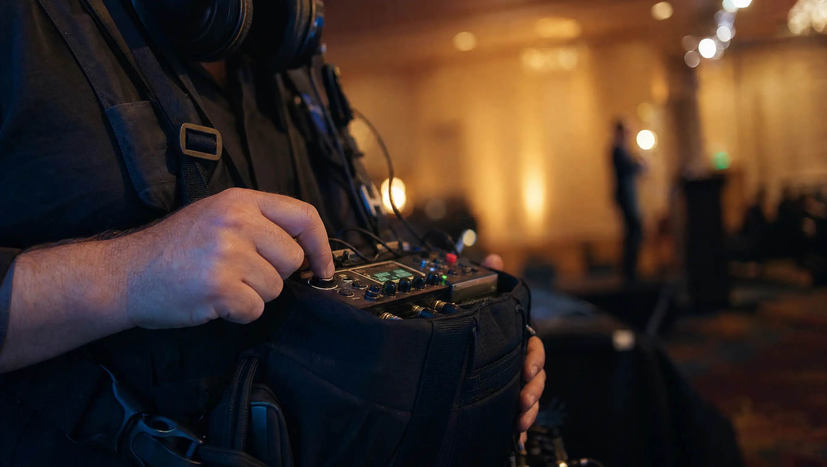 Sound recordist's hand on a field recorder during event videography of a keynote.