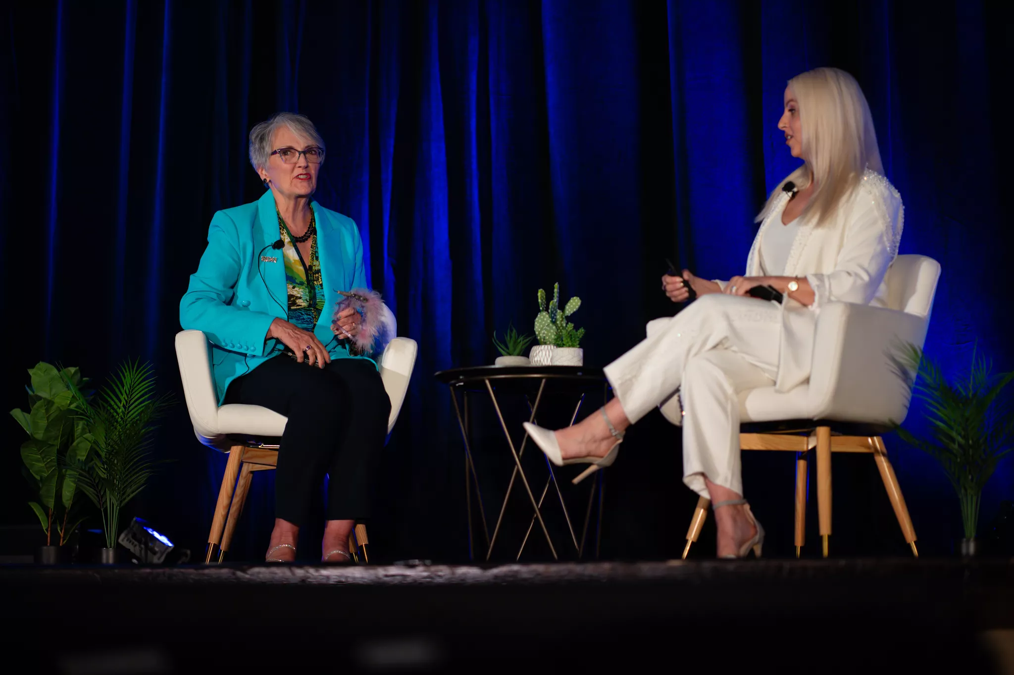Fireside chat between two speakers on stage at a corporate event.