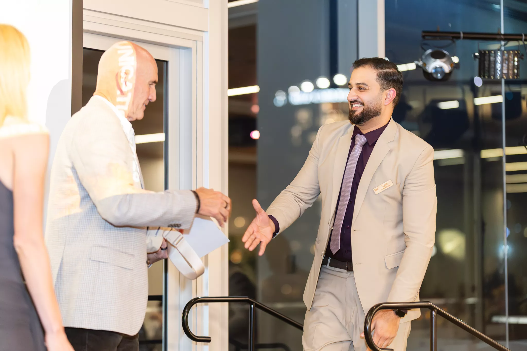 Event host welcoming an arriving attendee at a corporate event entrance