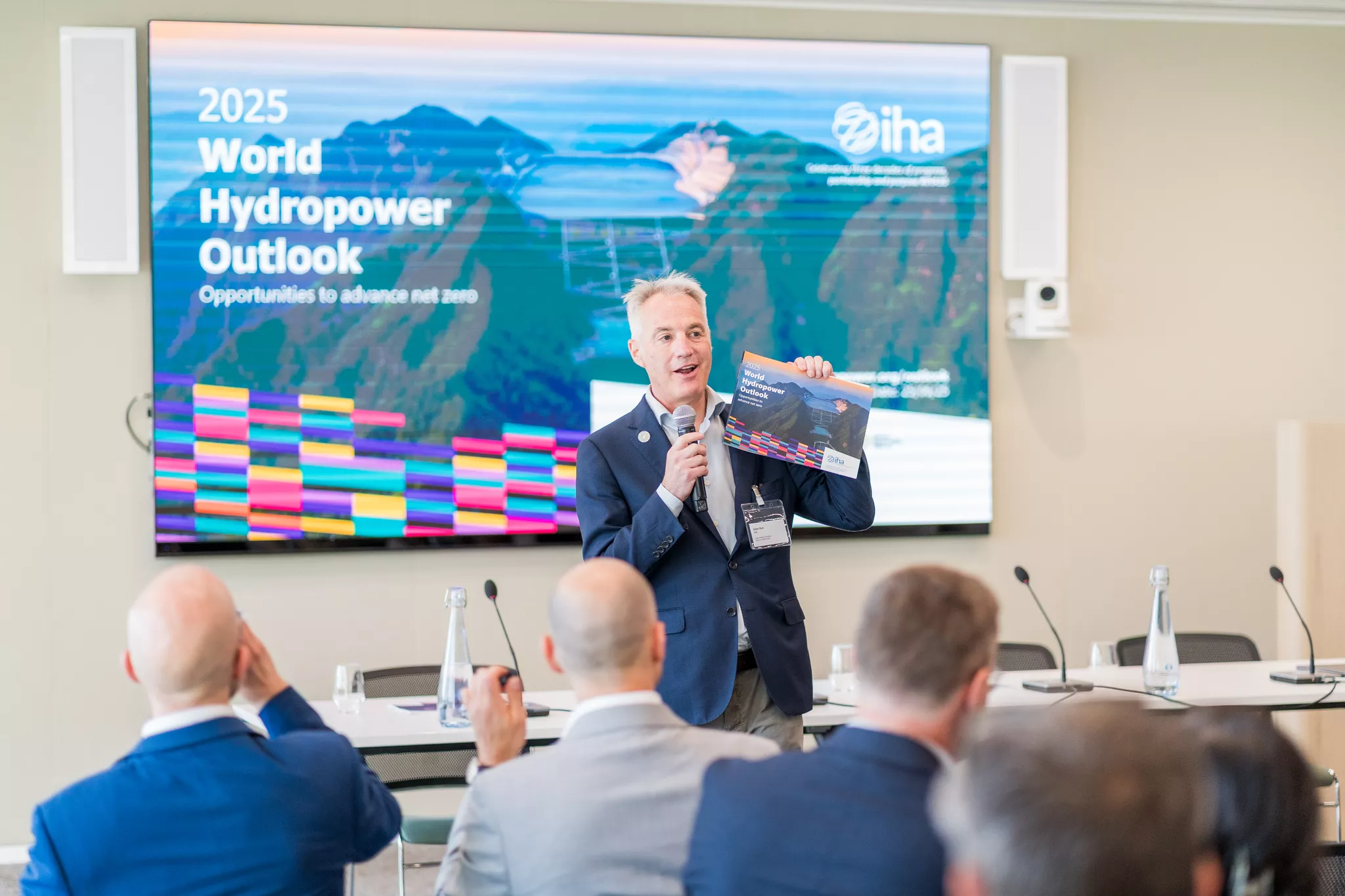 Corporate event photographer captures a speaker unveiling an industry report at a B2B summit.