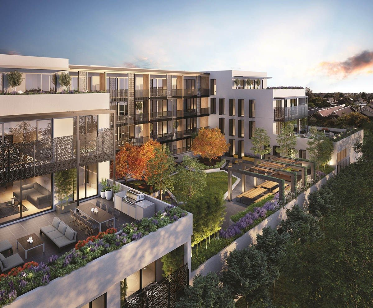Aerial view of a modern apartment complex with rooftop terraces, landscaped gardens, and outdoor seating areas at sunset