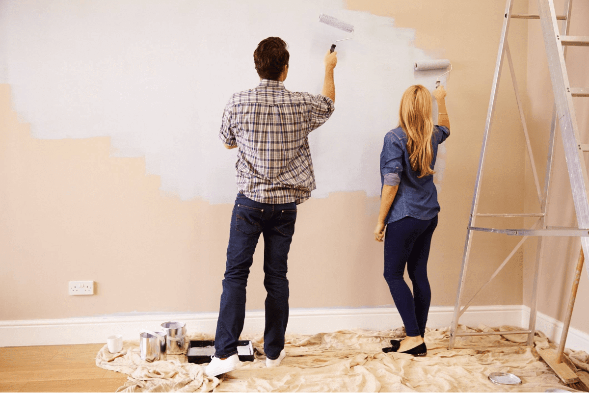 Couple painting an interior wall together as a DIY home improvement project before selling
