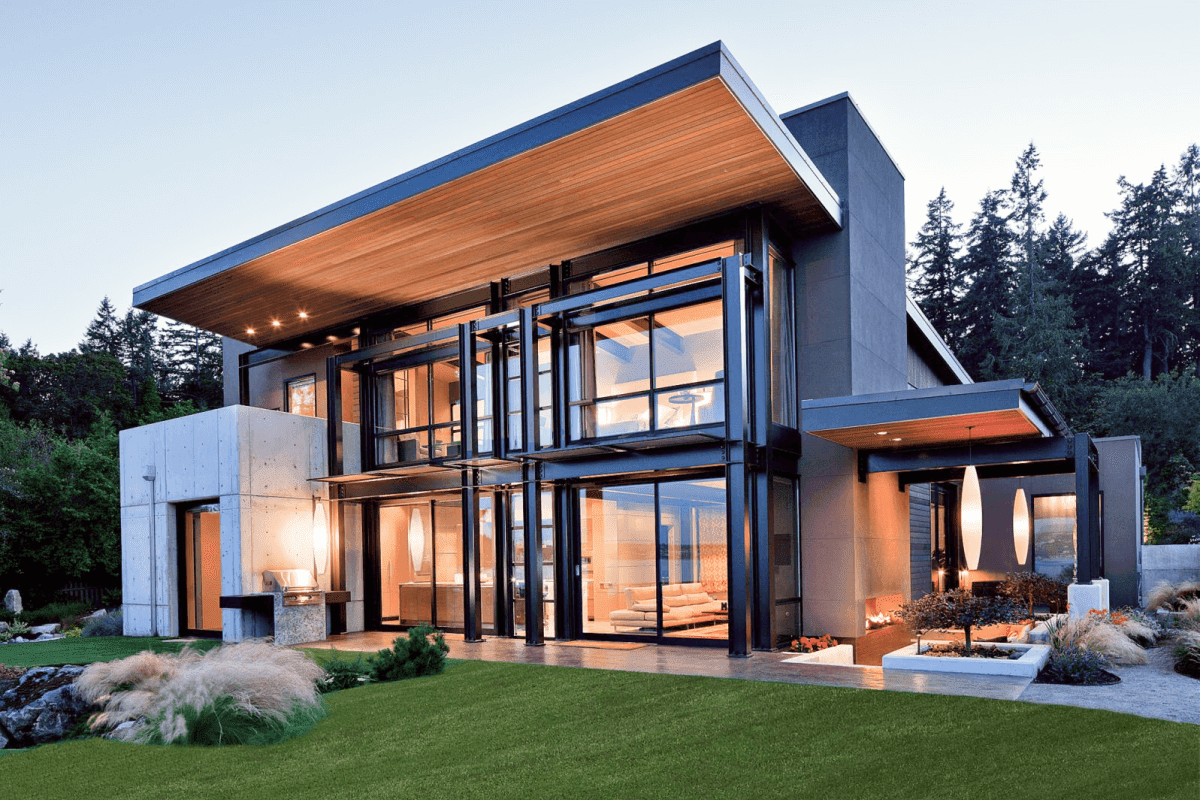 Contemporary gray home exterior with steel beams and floor-to-ceiling glass windows at dusk