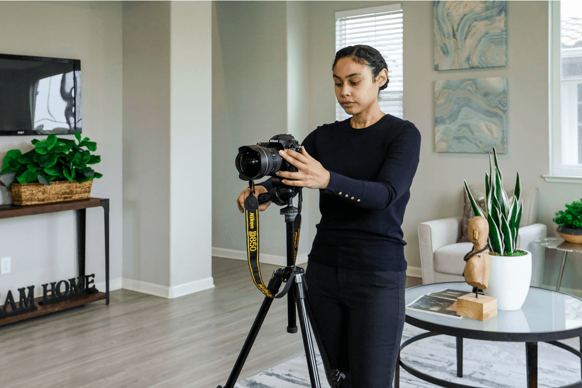 Real estate photographer setting up camera on tripod in a staged living room