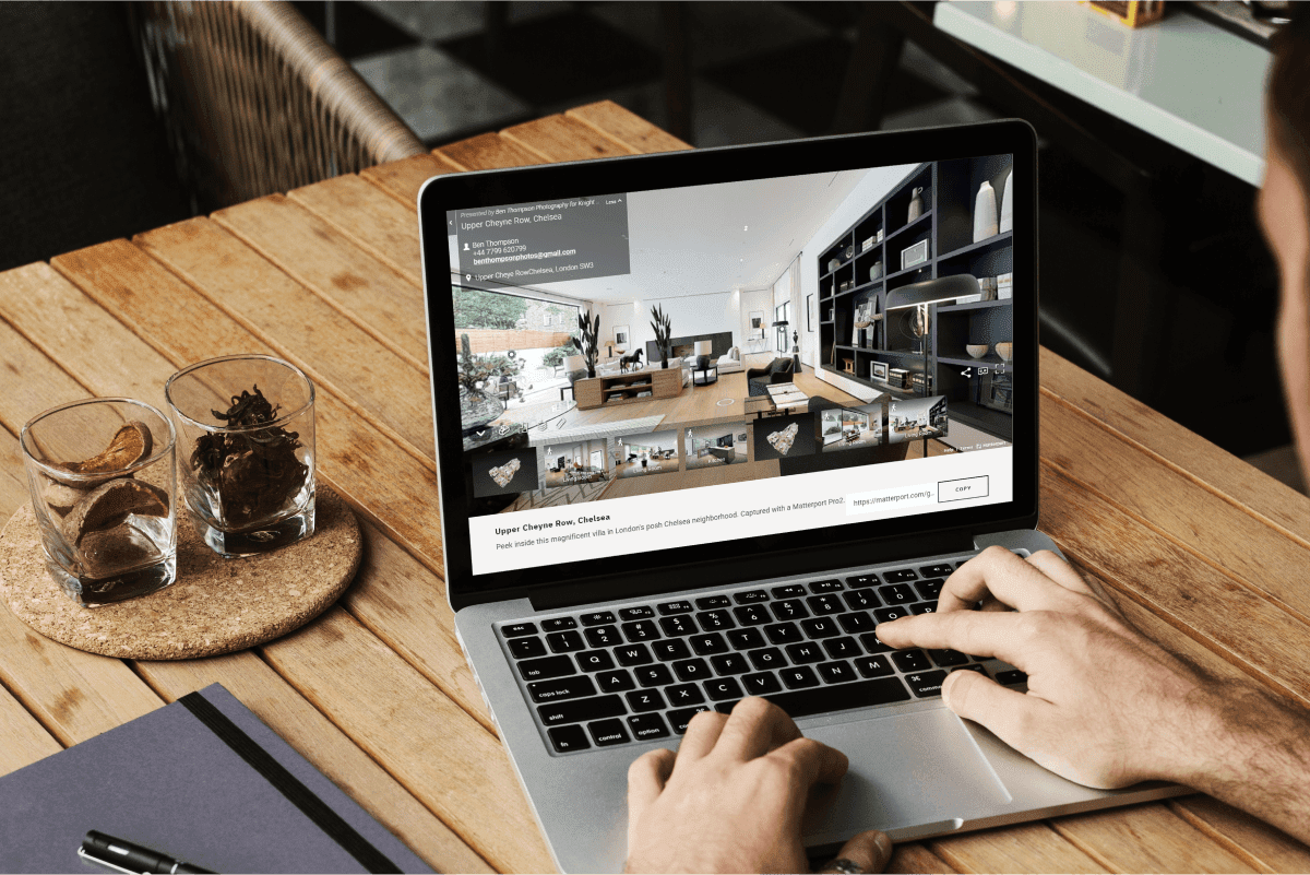 Homebuyer browsing a virtual property tour on a laptop at a wooden desk, representing the sight-unseen home buying trend