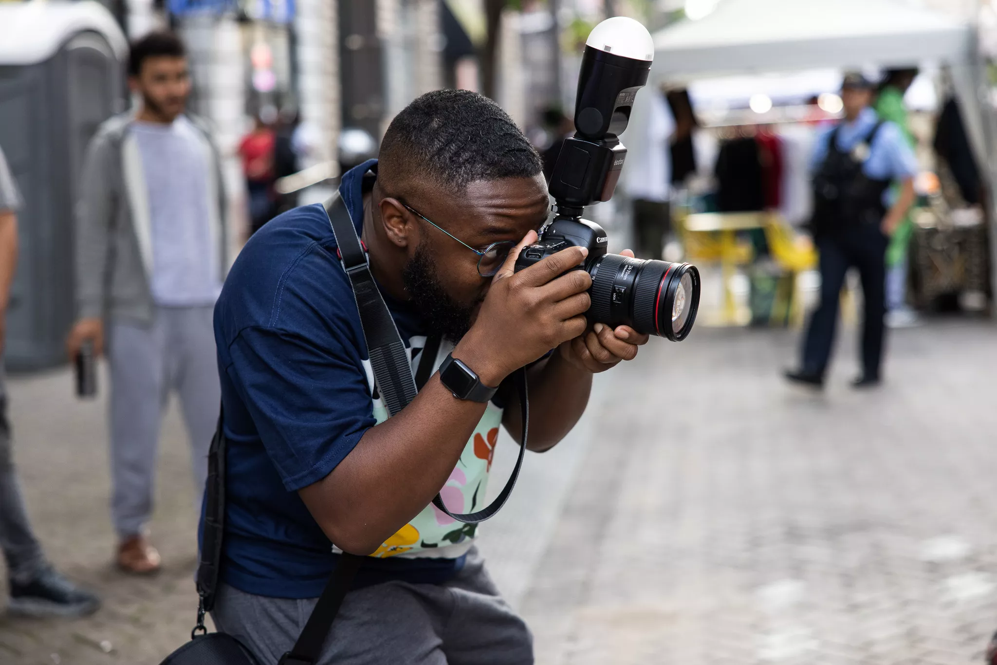 Event photographer shooting with a Canon DSLR and flash at a street market .