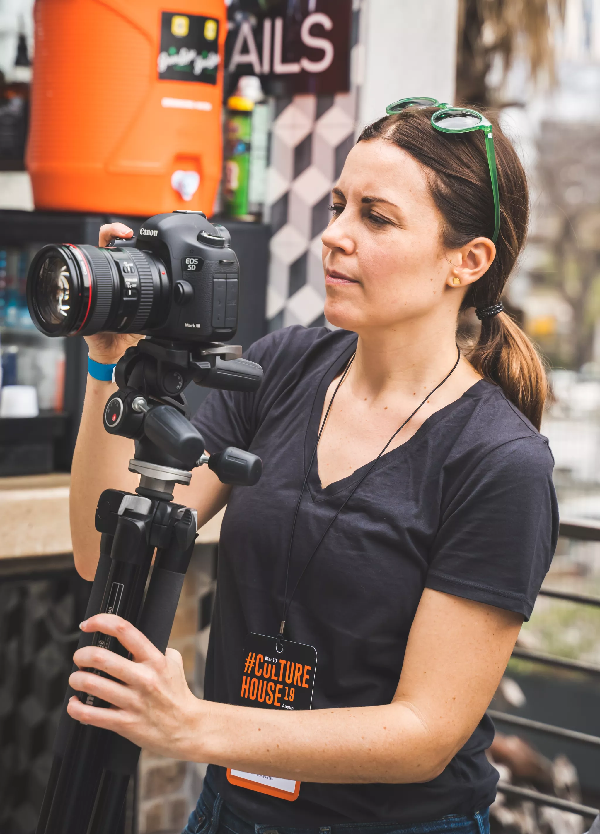 Event photographer setting up a Canon DSLR on a tripod at an outdoor festival.