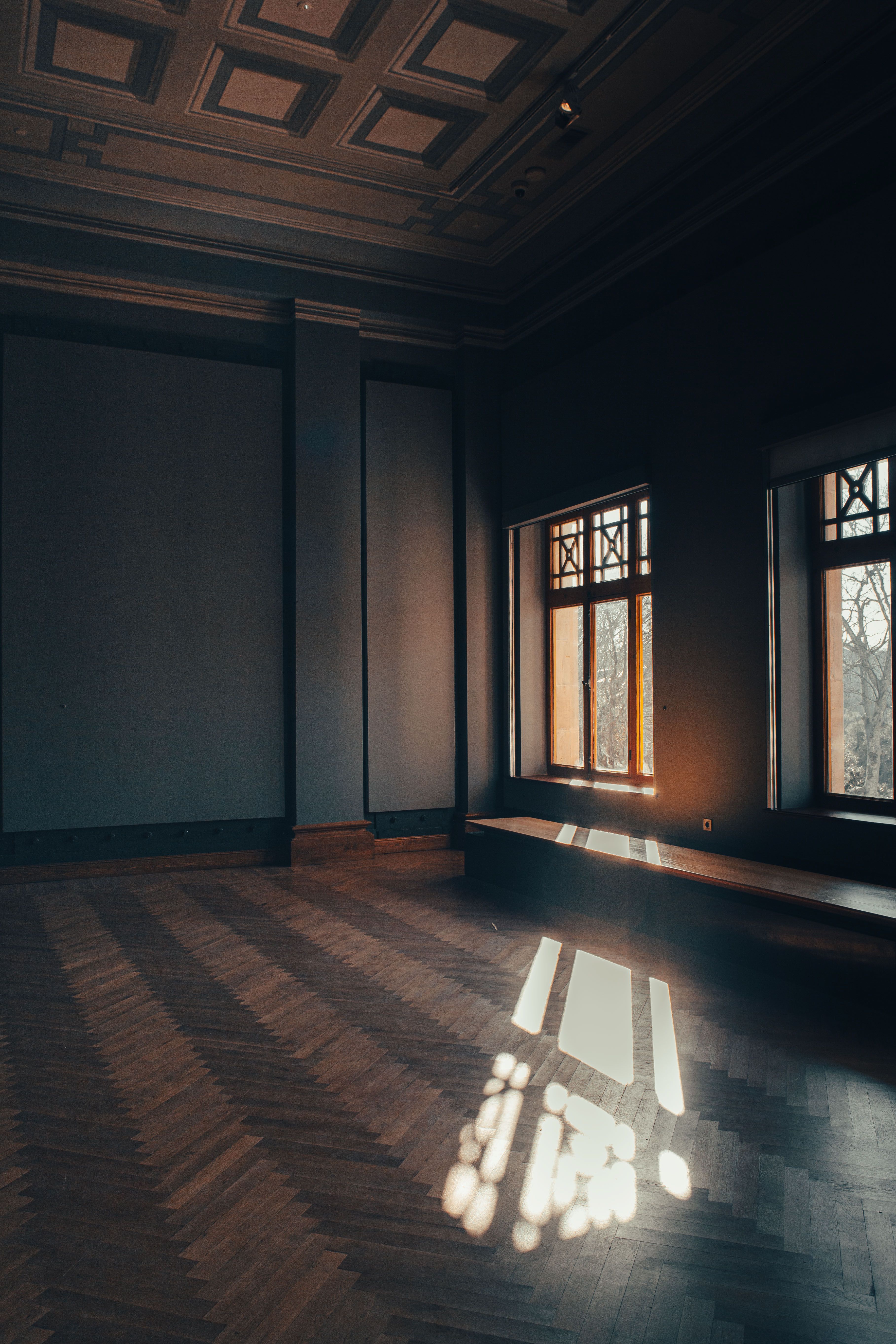 Empty room with herringbone floors and tall windows before any virtual staging.