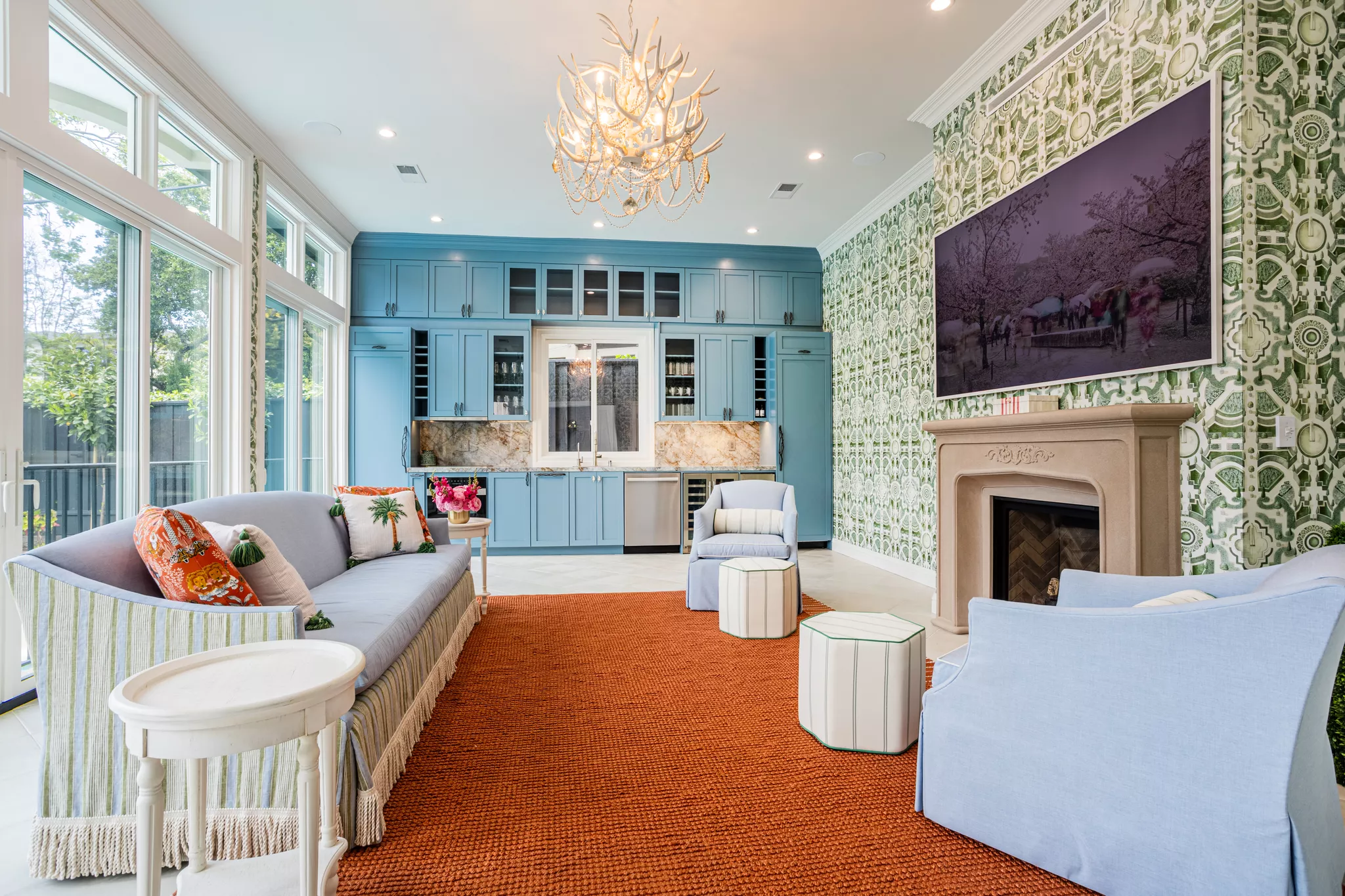 Designer living room staged with blue sofas, orange rug, and antler chandelier .