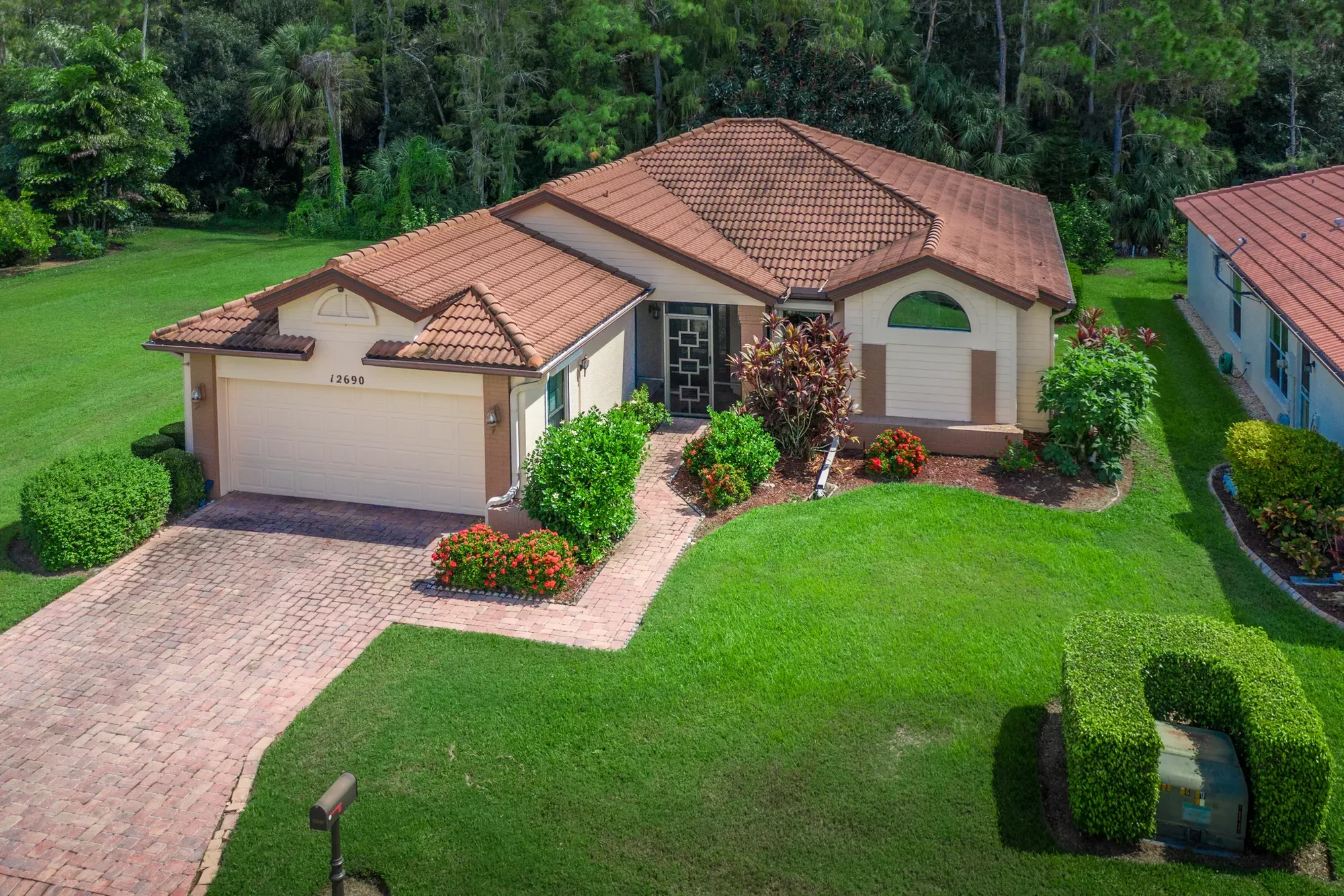 Aerial view of a single-story Florida home with tile roof and paver driveway.