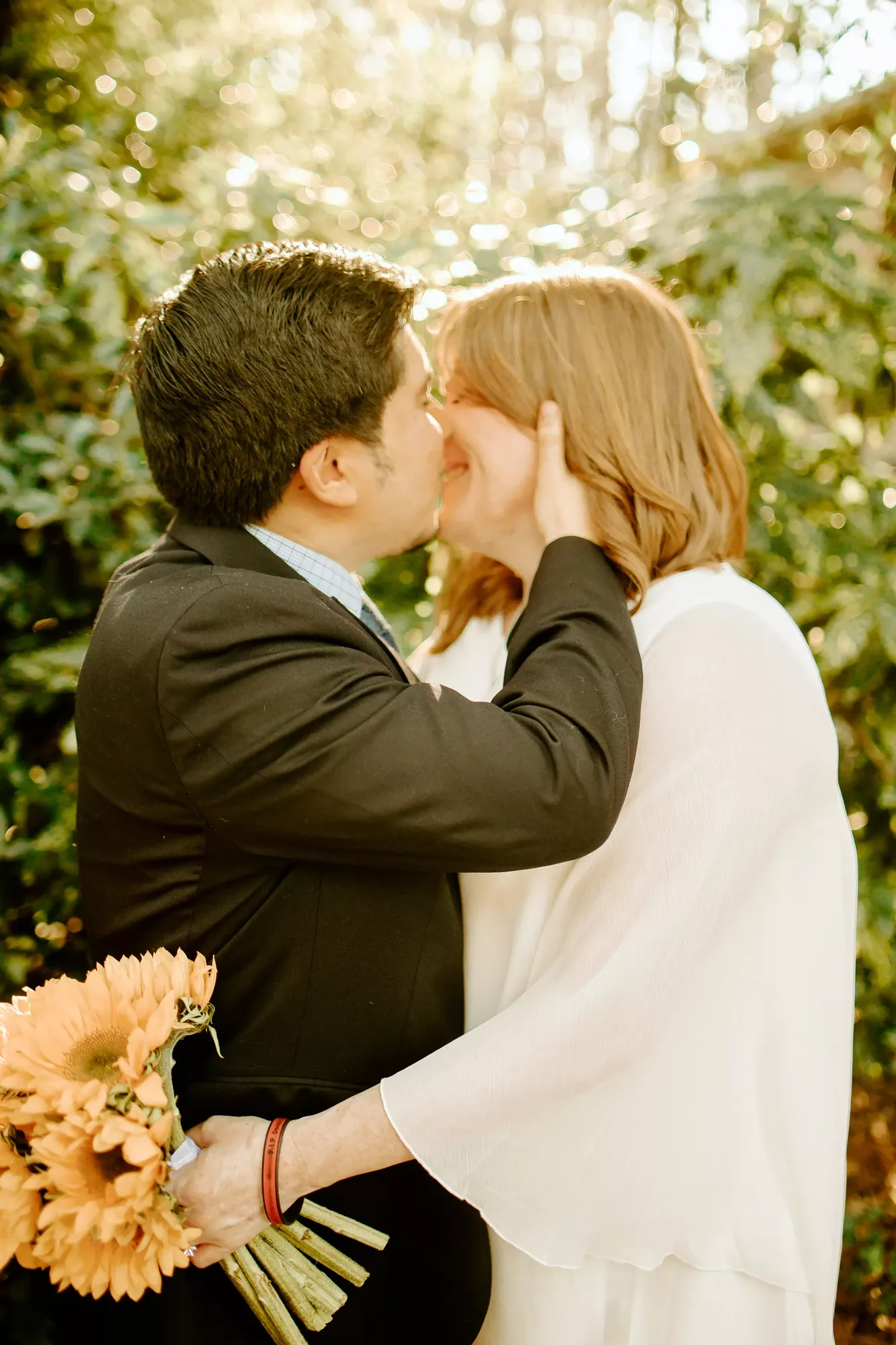 Quality wedding photographer captures a couple's kiss with a sunflower bouquet.