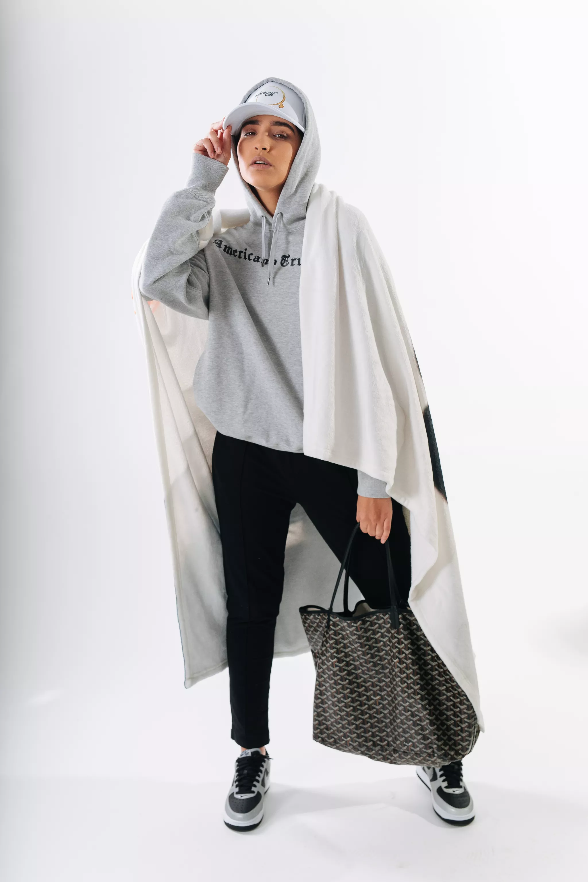 On-model apparel photography of a grey hoodie styled with black pants in a studio