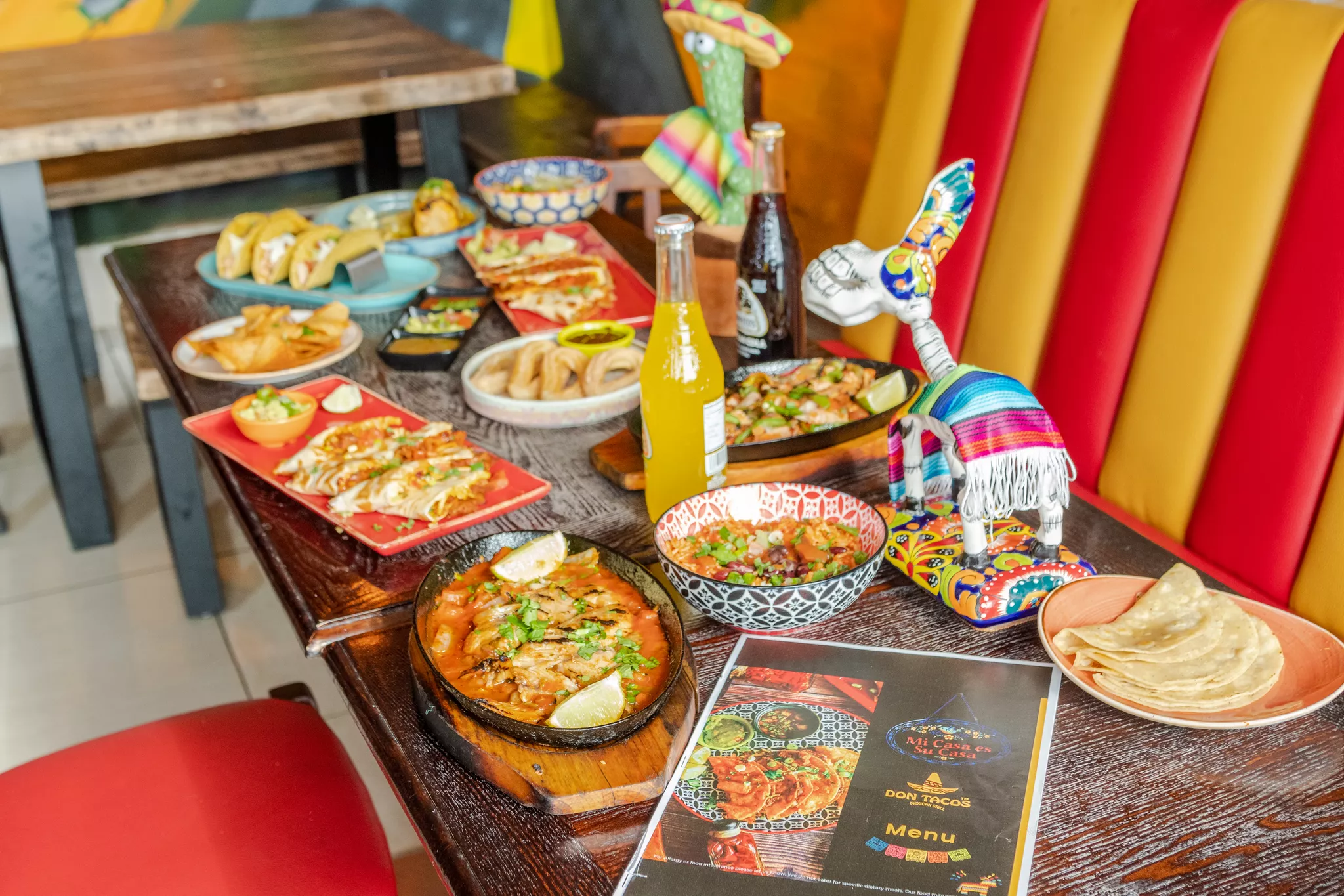 Photo-led Mexican restaurant menu resting beside sizzling fajitas, tacos and churros.