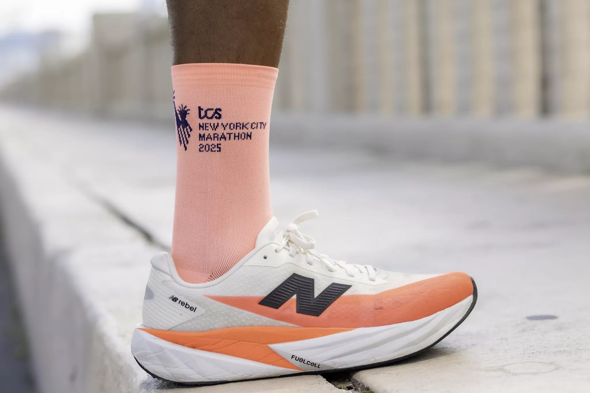 Lifestyle product photography of an orange and white running shoe on a concrete ledge.
