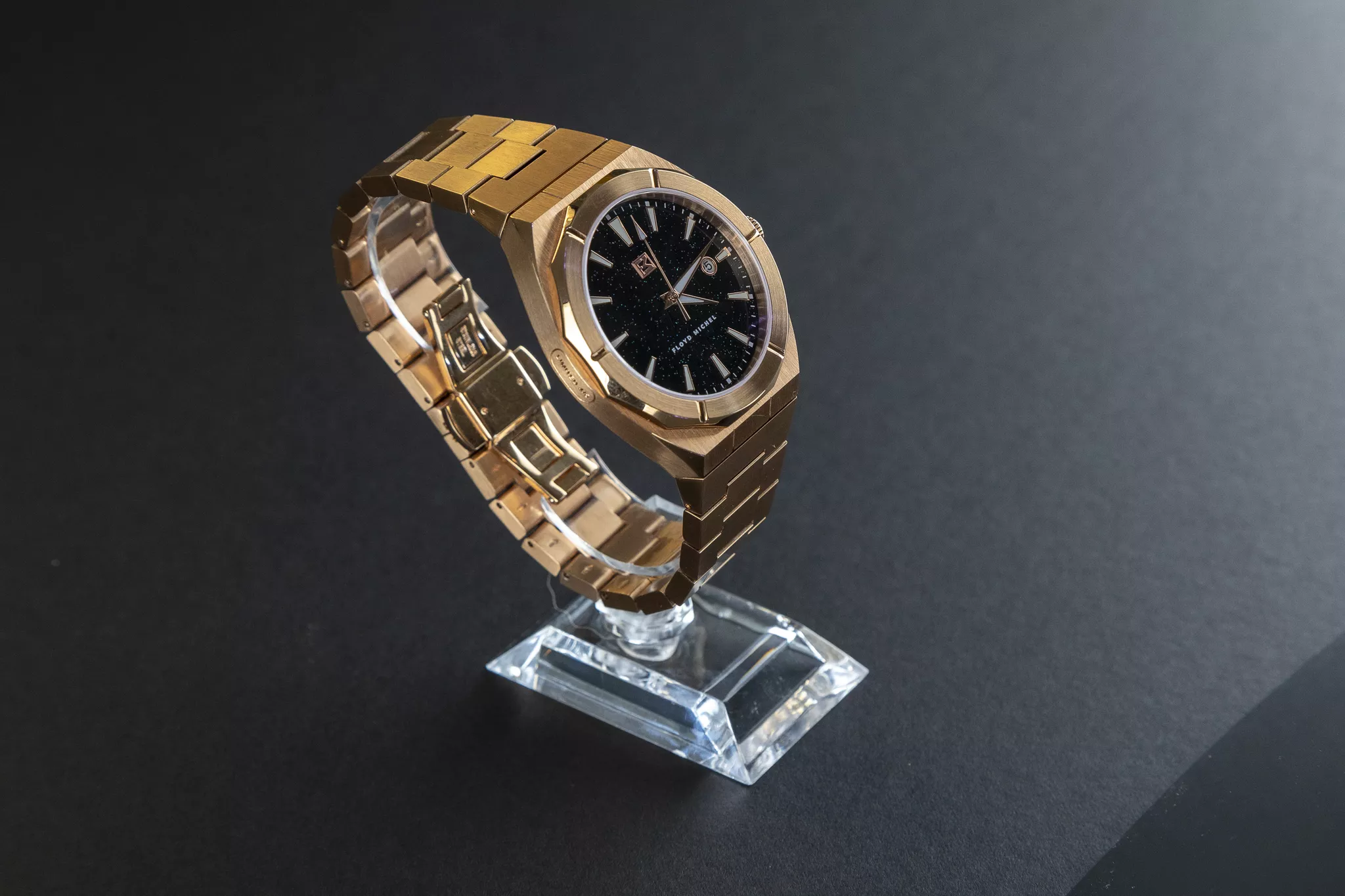 Hero product photography of a rose-gold watch with a black dial on a dark background.