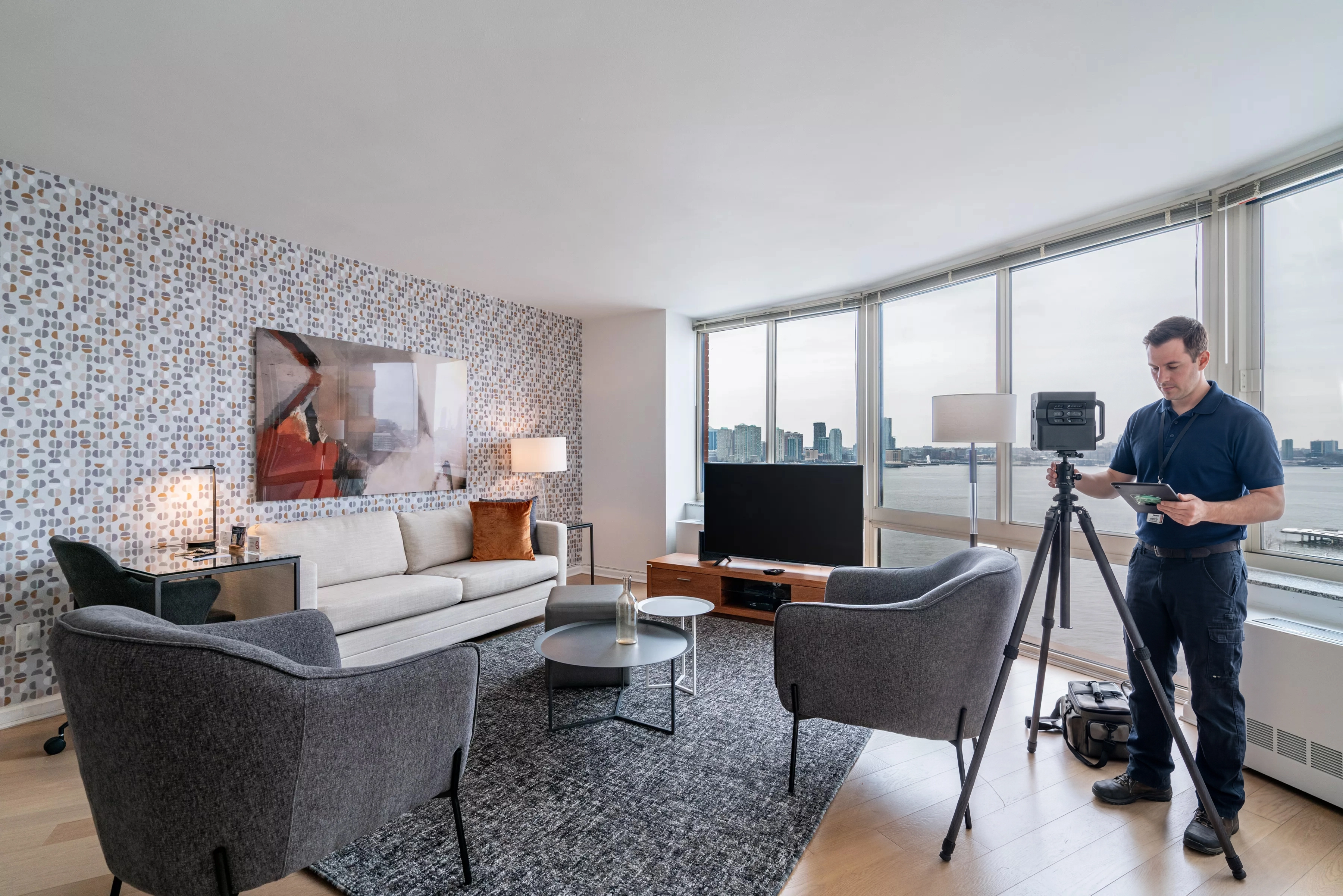 Matterport photographer operating a 3D camera on a tripod in a furnished apartment.