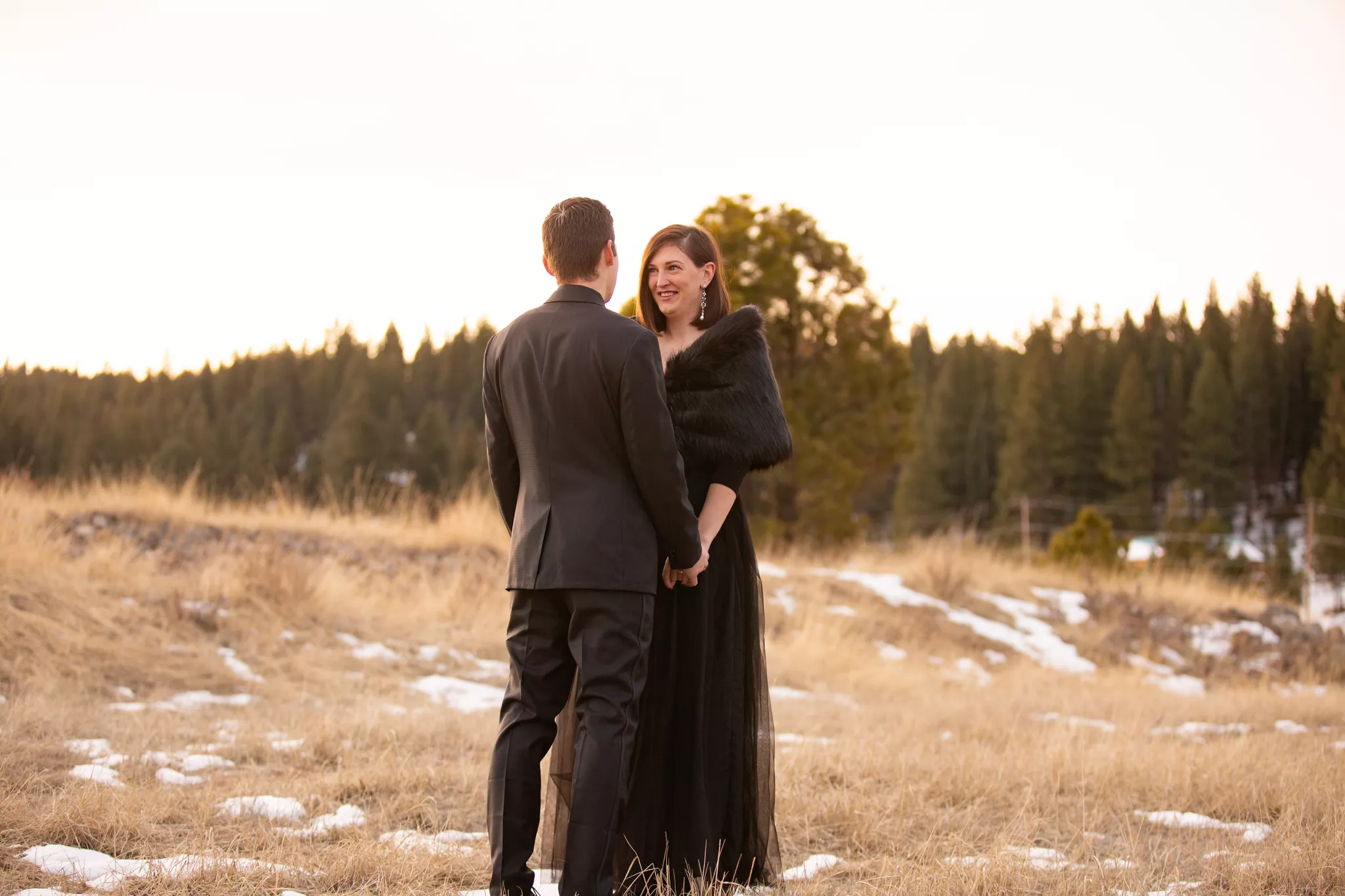 Engagement photo poses at golden hour — couple hold hands, her face over his shoulder