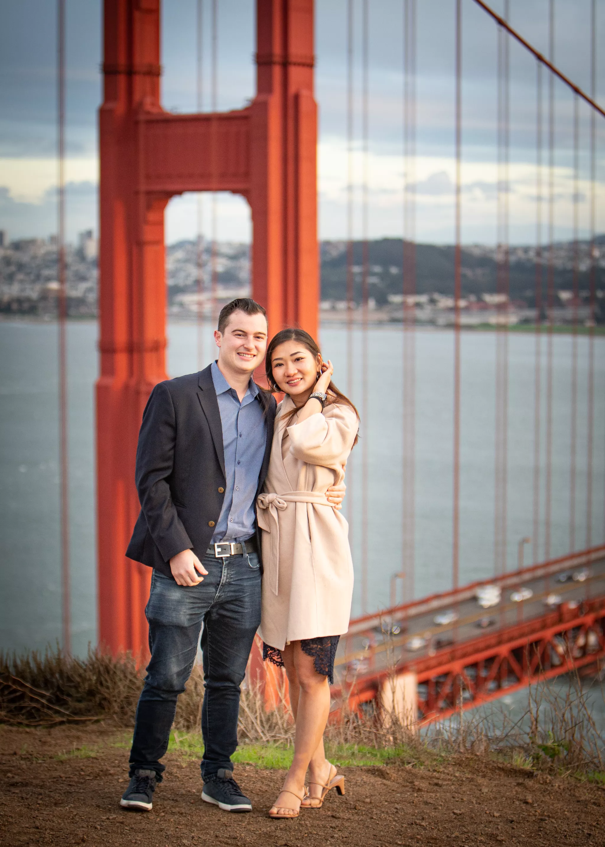 Engagement photo poses at the Golden Gate Bridge — couple standing close, his arm at her waist.