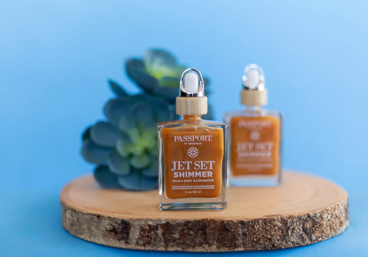Two Passport to Organics Jet Set Shimmer bottles styled on a wood slice, an example of professional product photography
