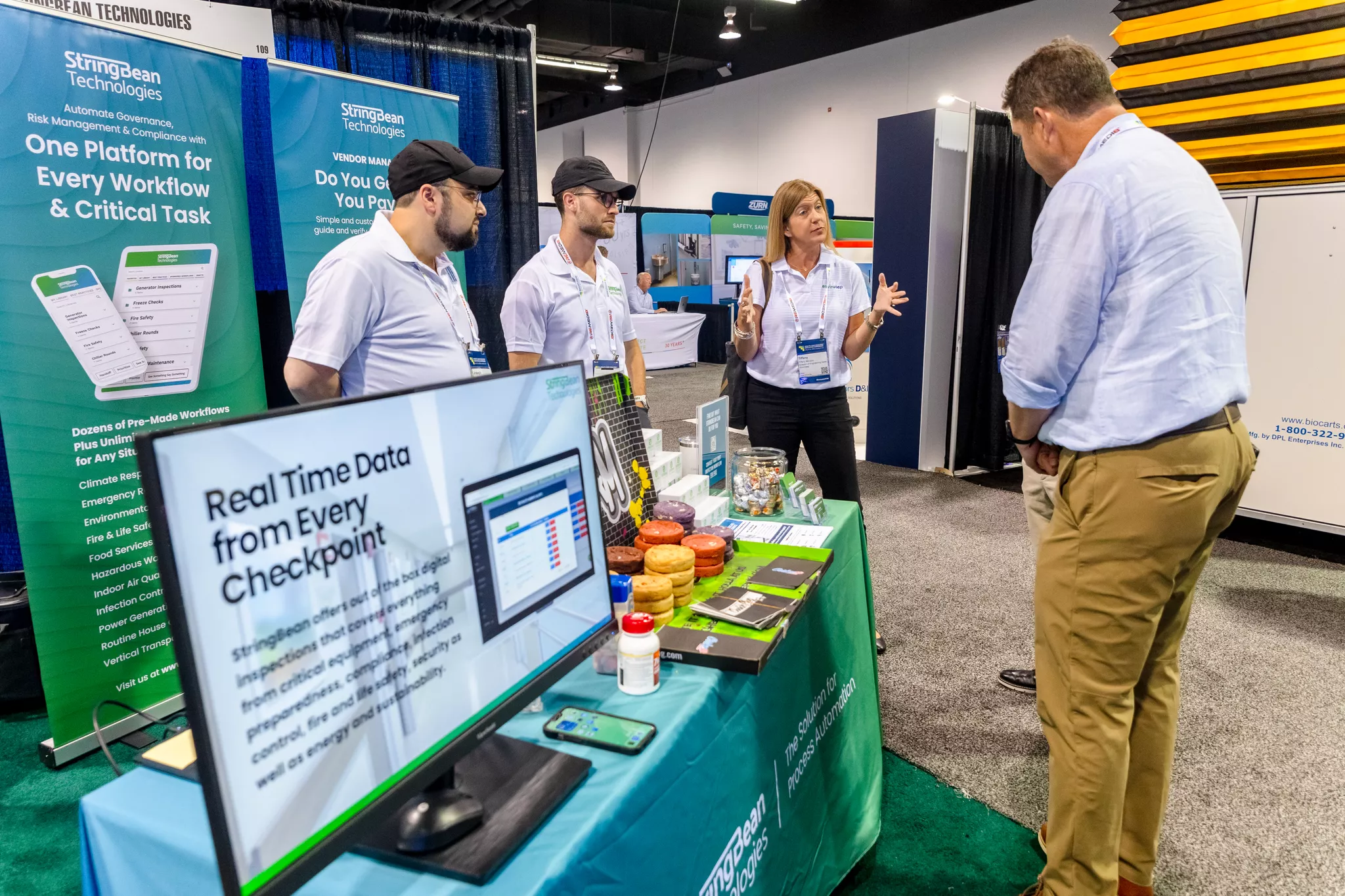 StringBean Technologies staff talk with an attendee at their trade show booth demo station