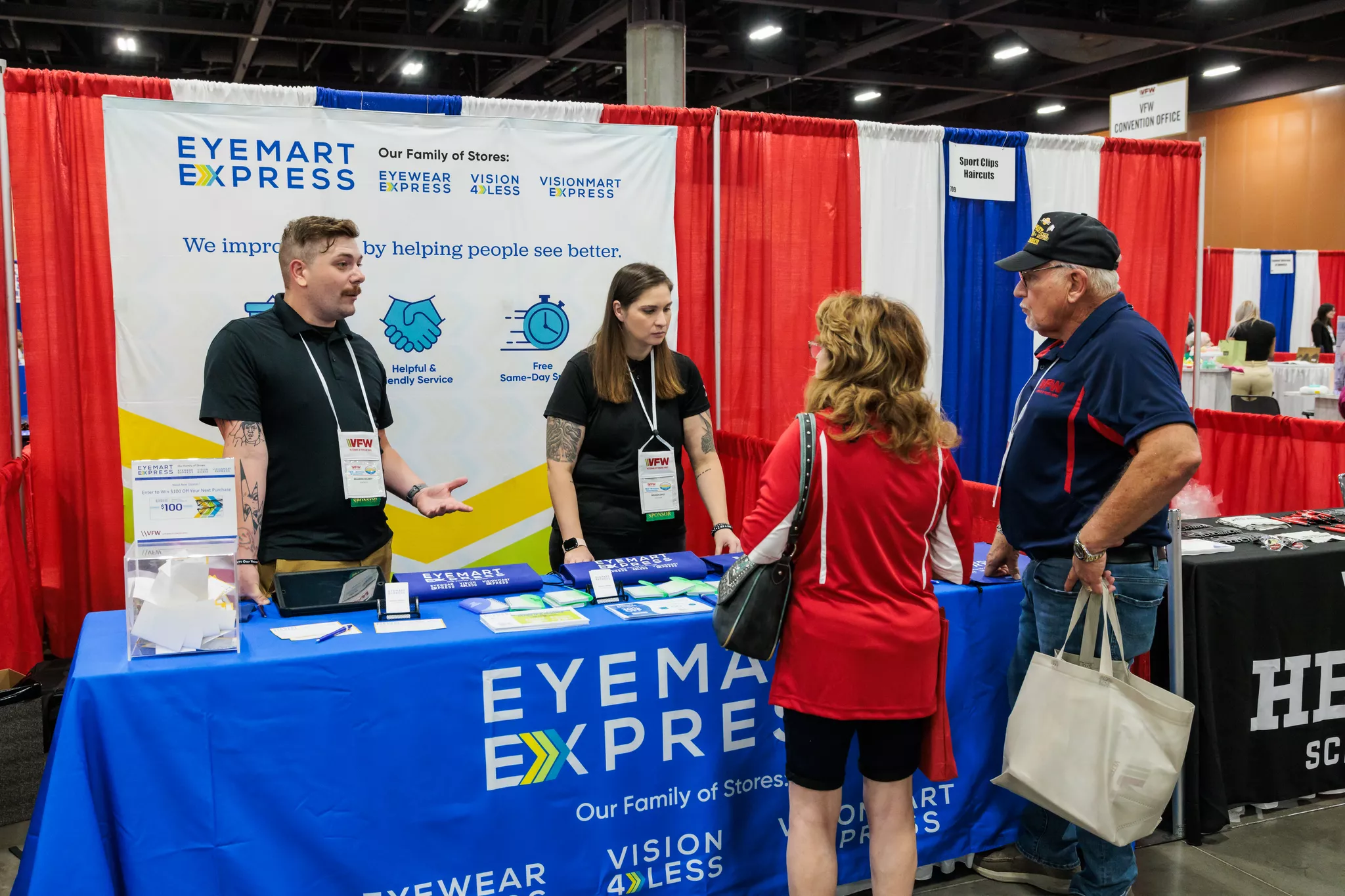 Eyemart Express booth staff speak with two attendees at a VFW convention trade show.