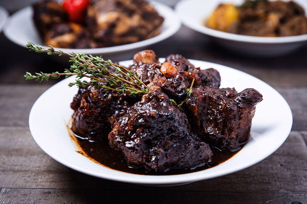 Braised beef in dark gravy garnished with fresh thyme, plated for restaurant menu photography
