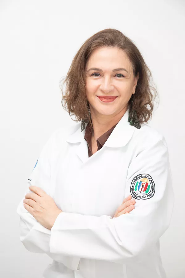 Dentist in a white coat photographed on a white backdrop for corporate headshots