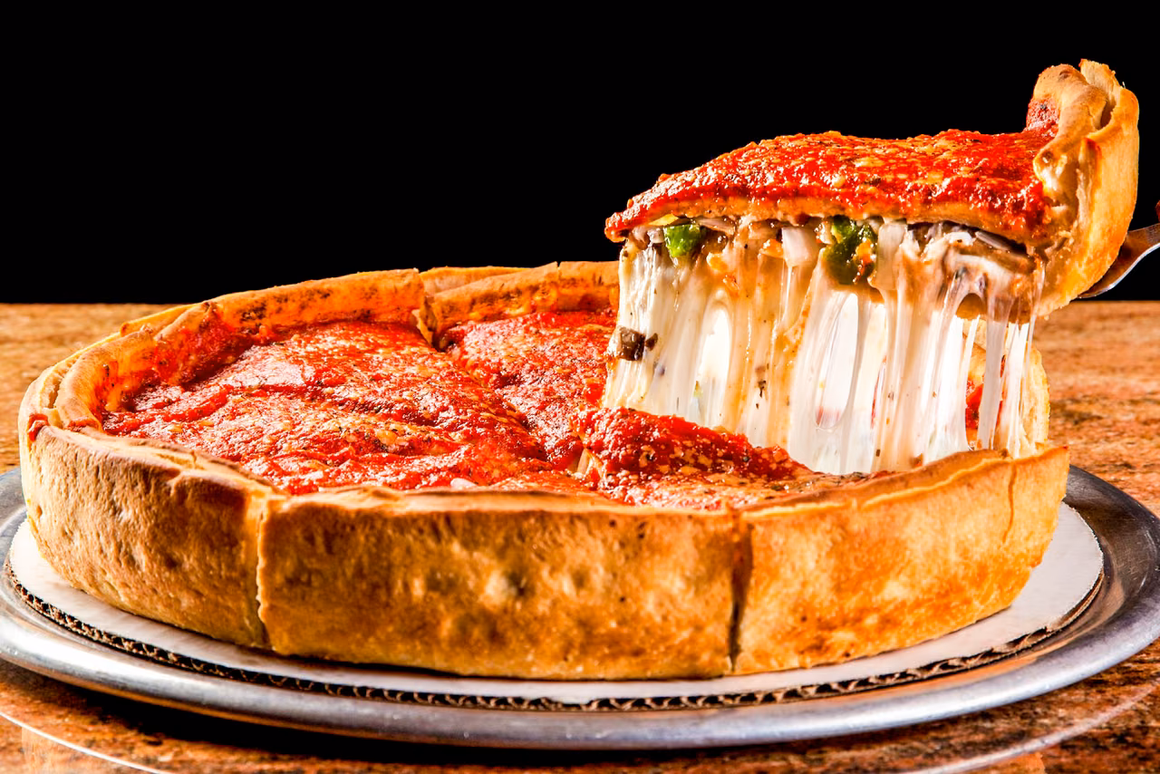 Chicago deep-dish pizza with a cheese pull as a slice is lifted from the pan