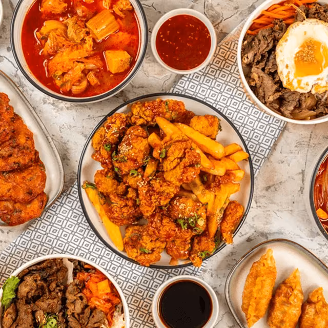 Assorted Korean dishes including fried chicken, rice bowls and spicy stew served on a table