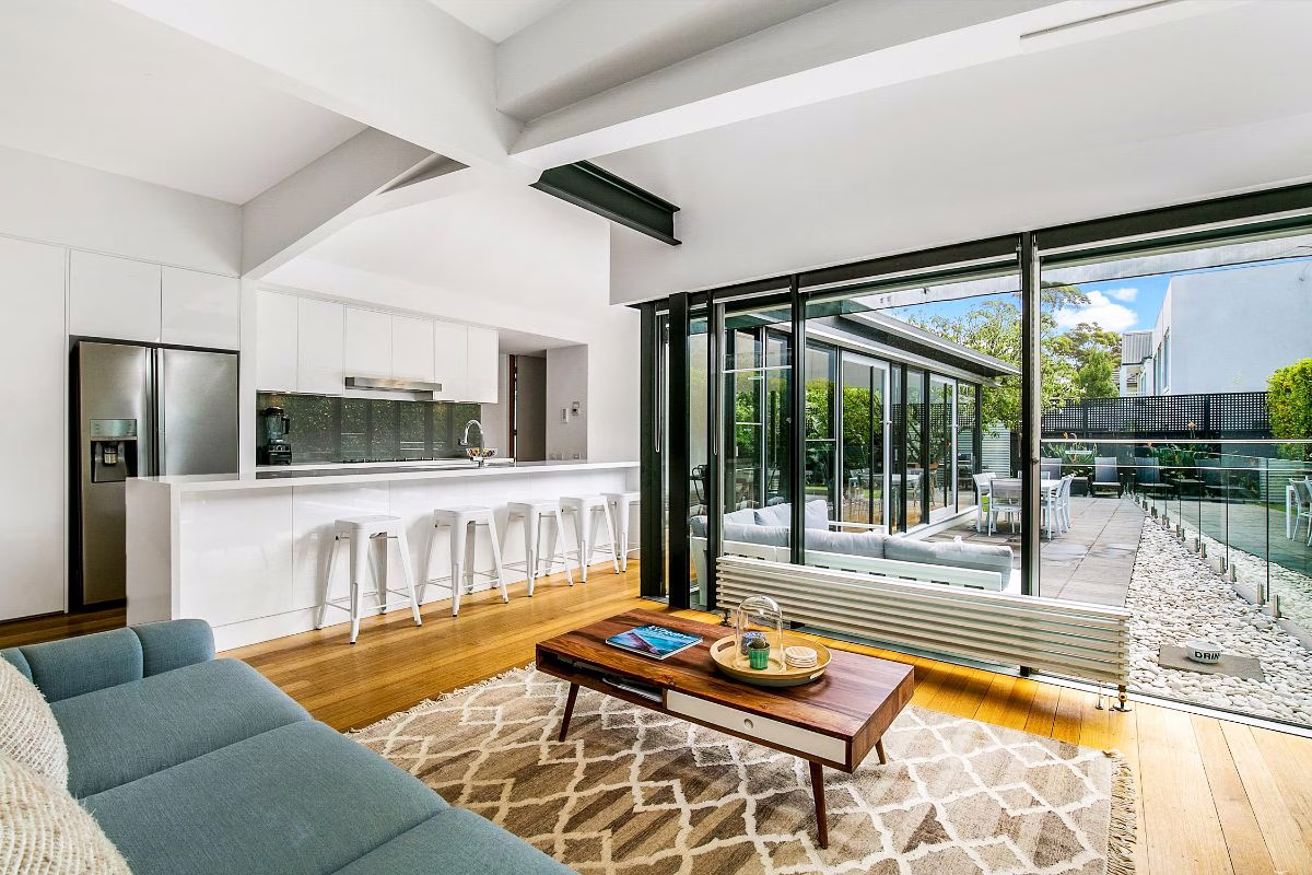 Professional real estate photo of an open-plan kitchen and living area opening onto a patio
