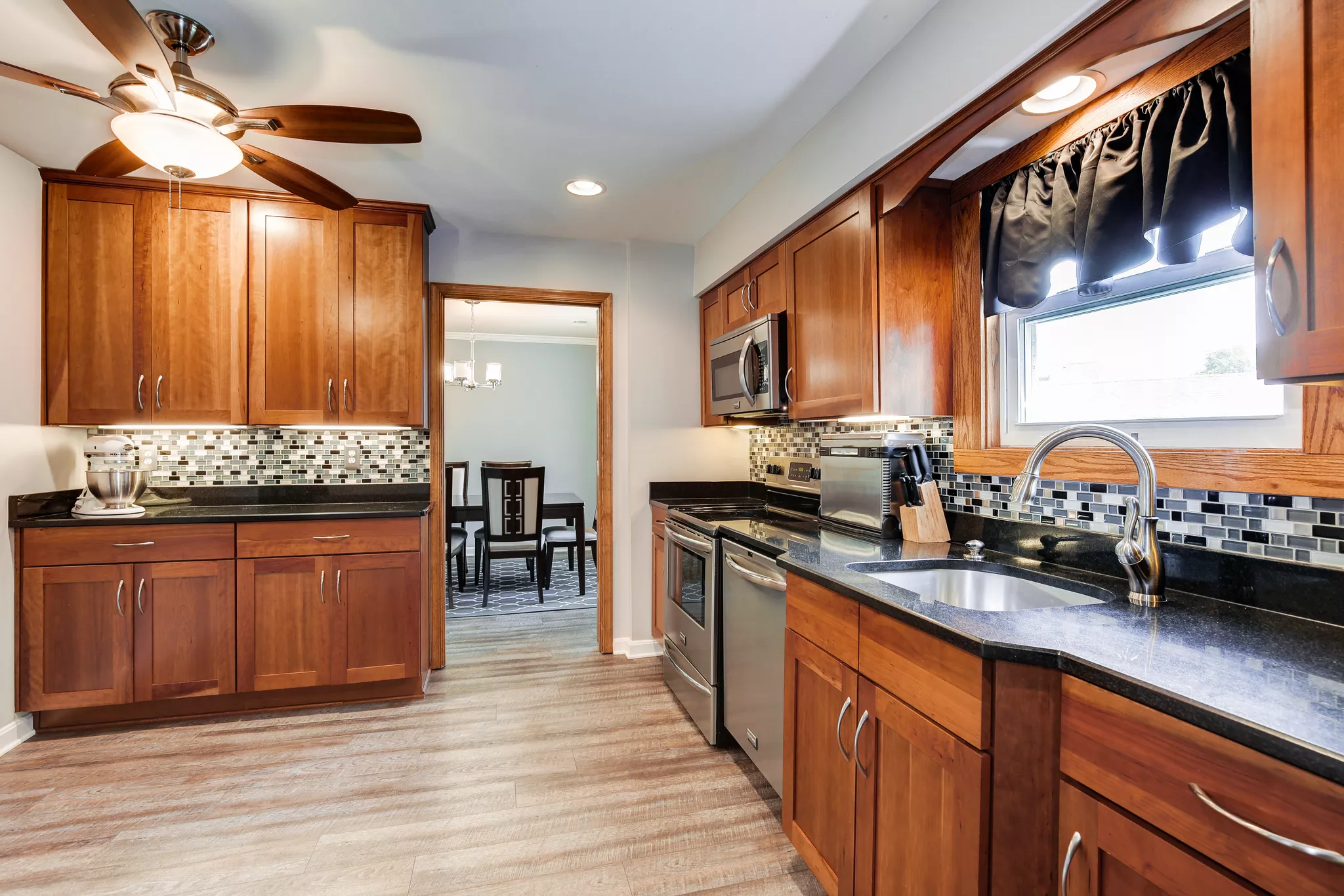 Real estate listing photo of a galley kitchen with wood cabinets and granite countertops