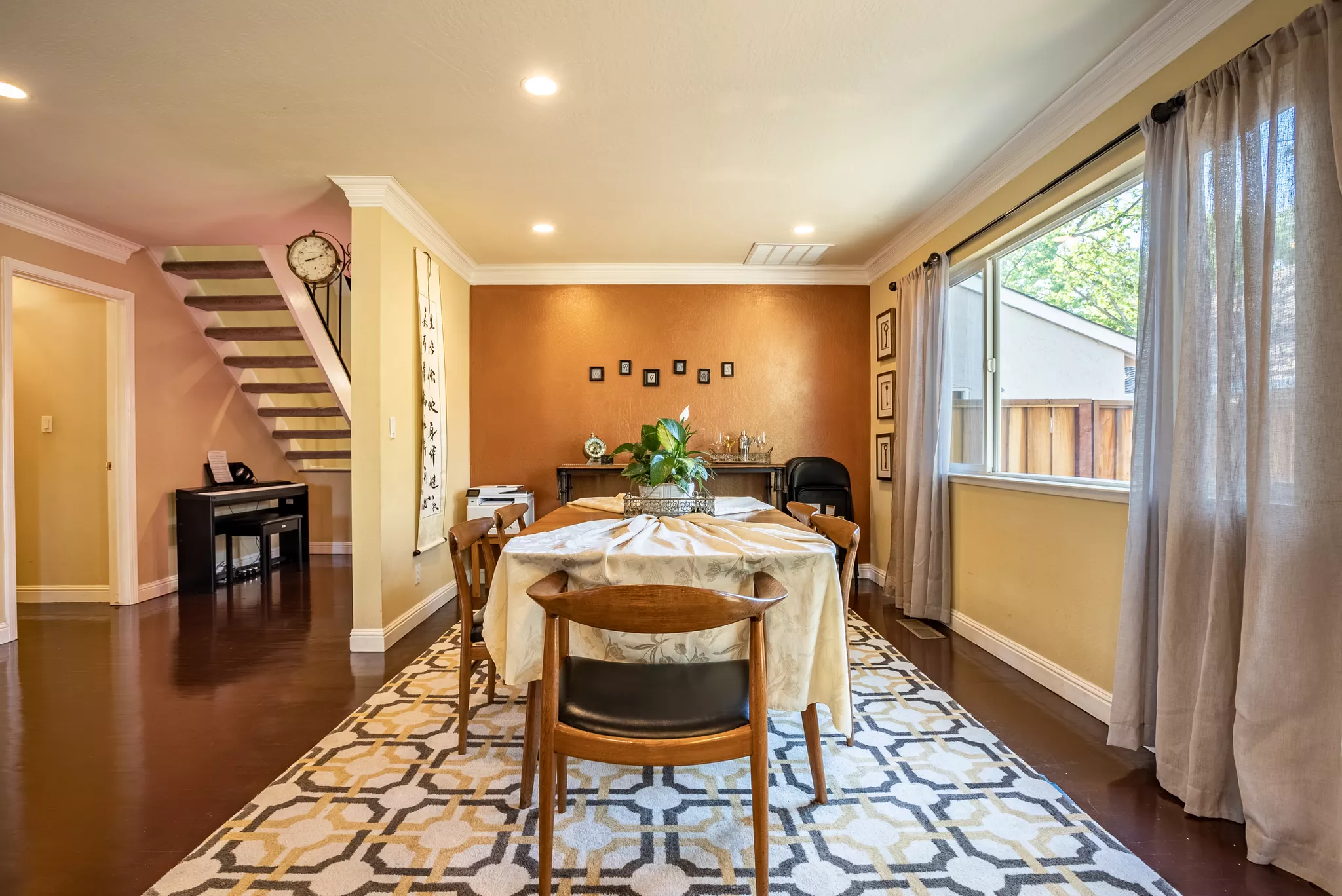 Real estate listing photo of a dining room with a terracotta accent wall and bright window.