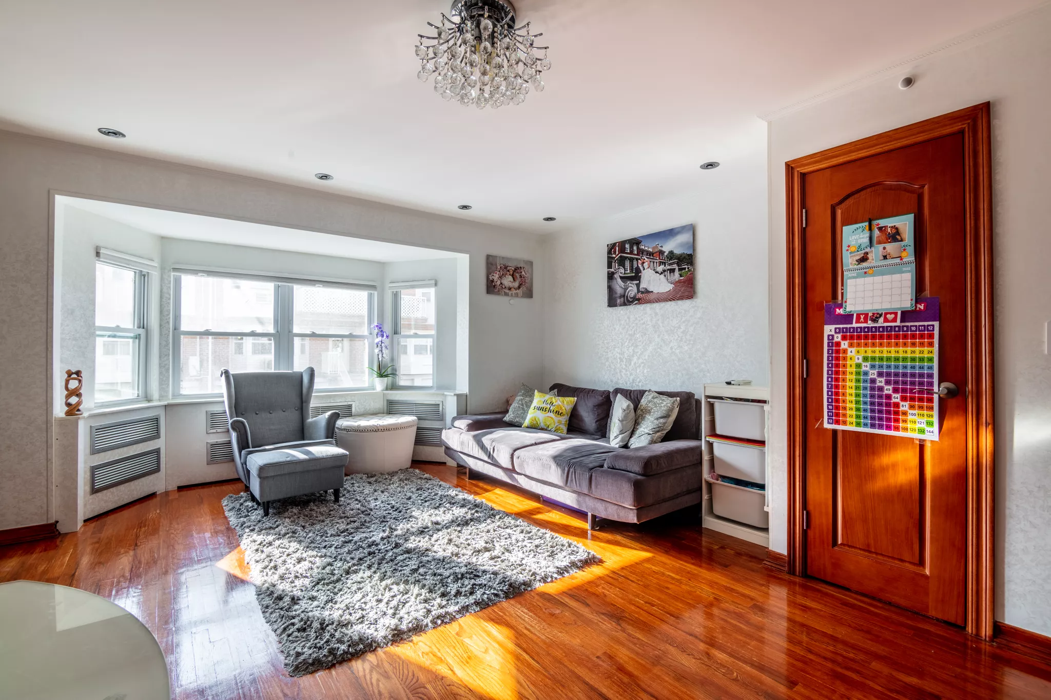 Real estate photography of a lived-in living room with a bay window and hardwood floors