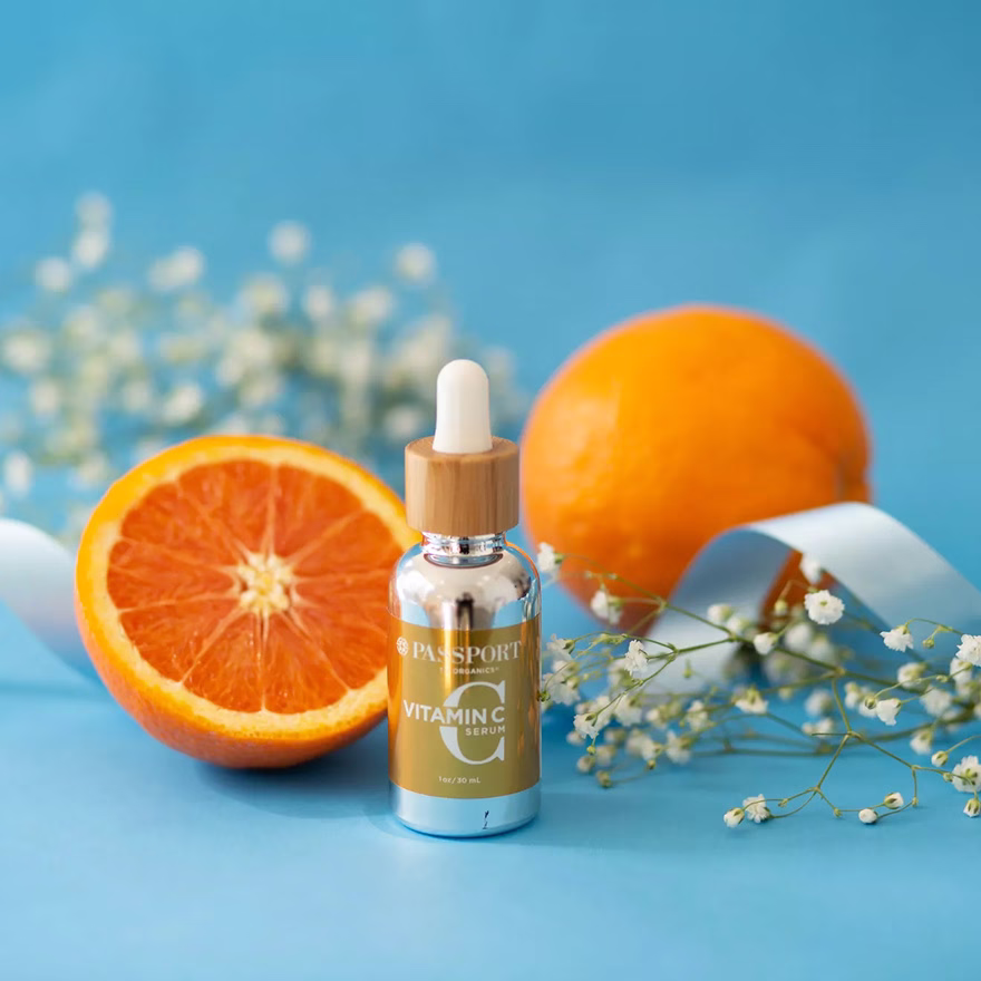 Vitamin C serum product styled in a vibrant orange flatlay against a blue background