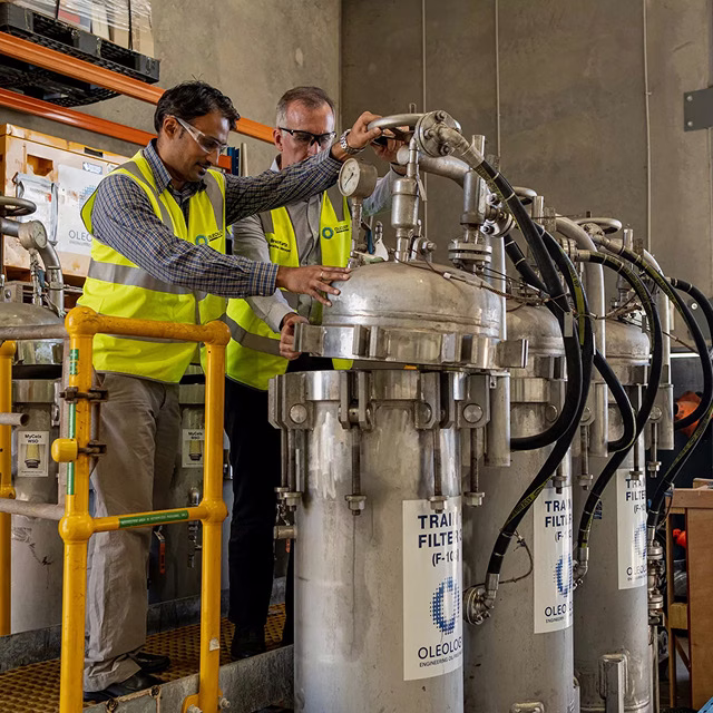 Engineers in hi-vis safety vests inspecting industrial equipment at a worksite.