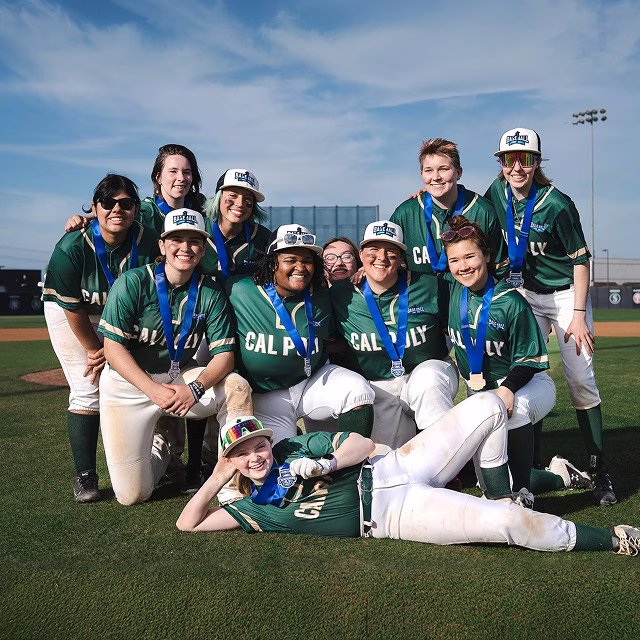 Cal Poly women's softball team posing together for a group photo while wearing their medals.