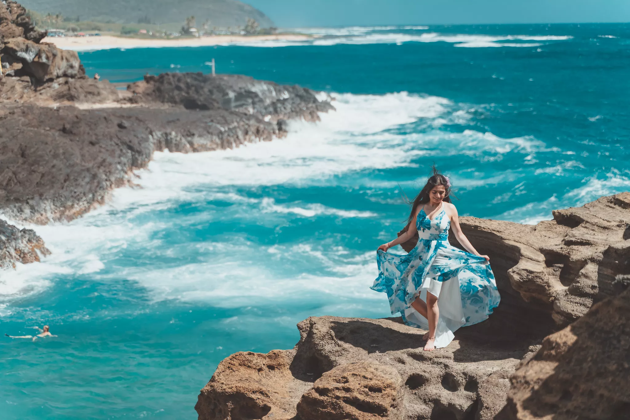 Photoshoot outfit in blue and white florals on a rock ledge above turquoise ocean surf