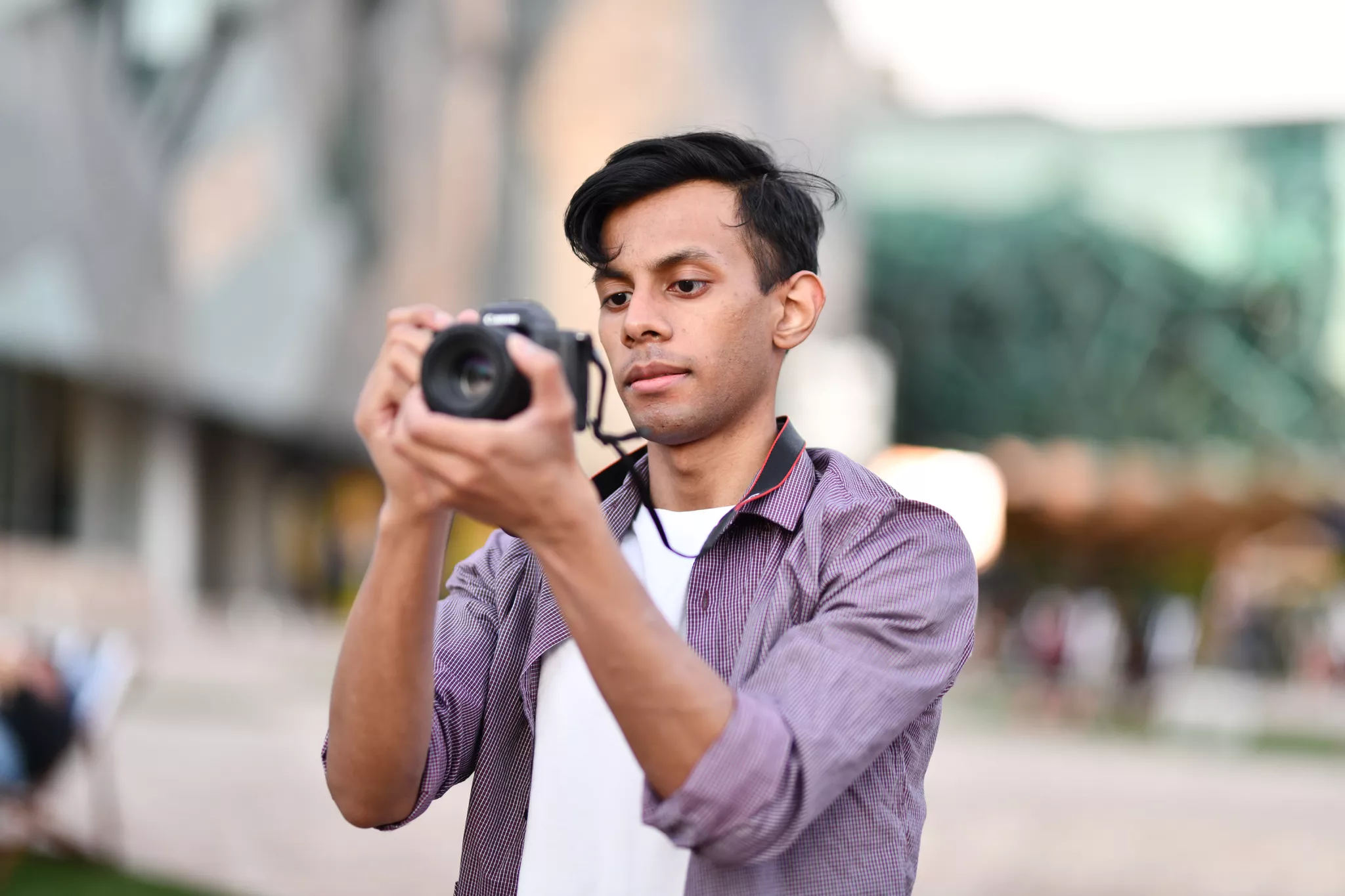 Photographer in a purple shirt framing a shot on a Canon DSLR at an outdoor session