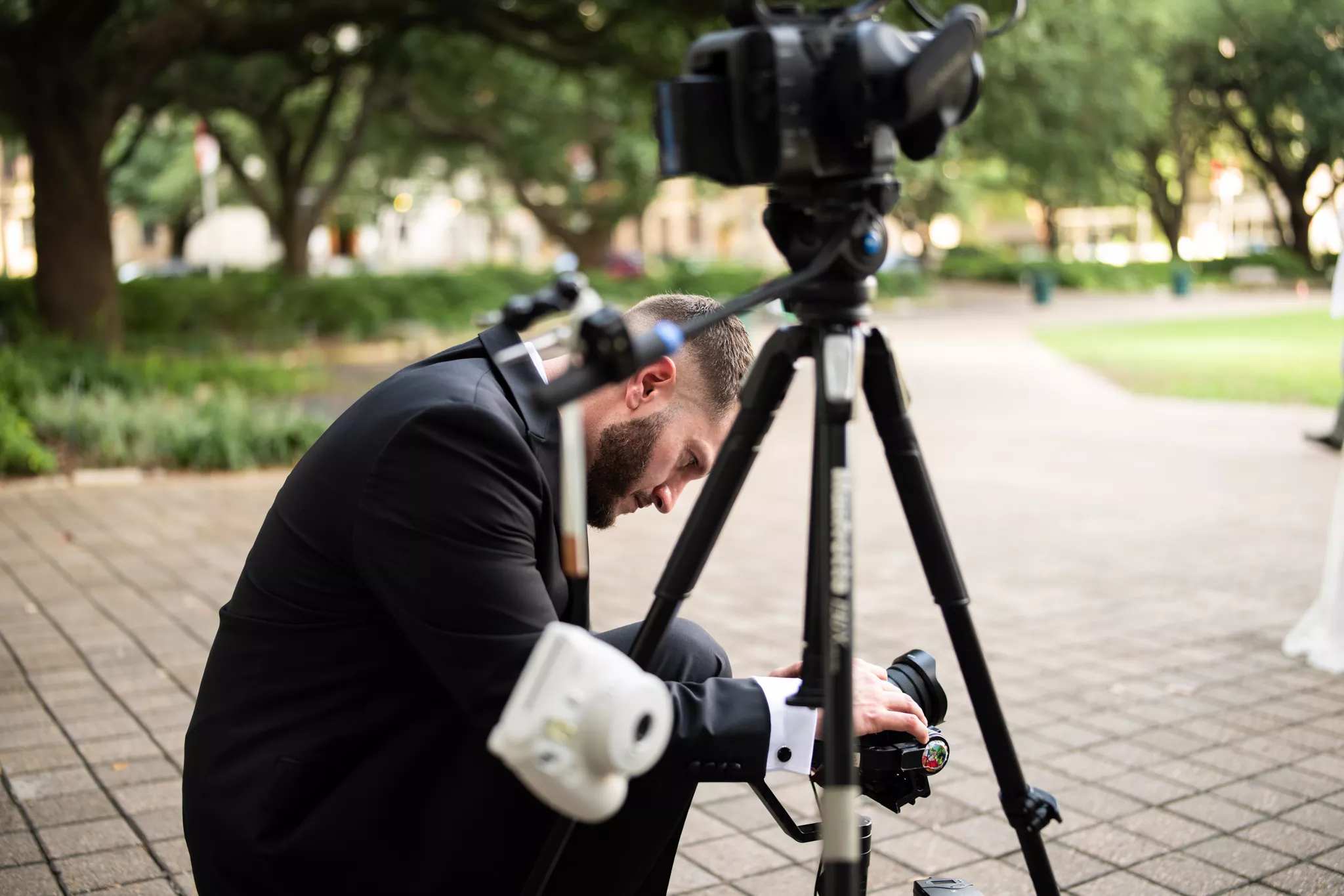 Videography services on location: a videographer sets up a tripod-mounted camera outdoors