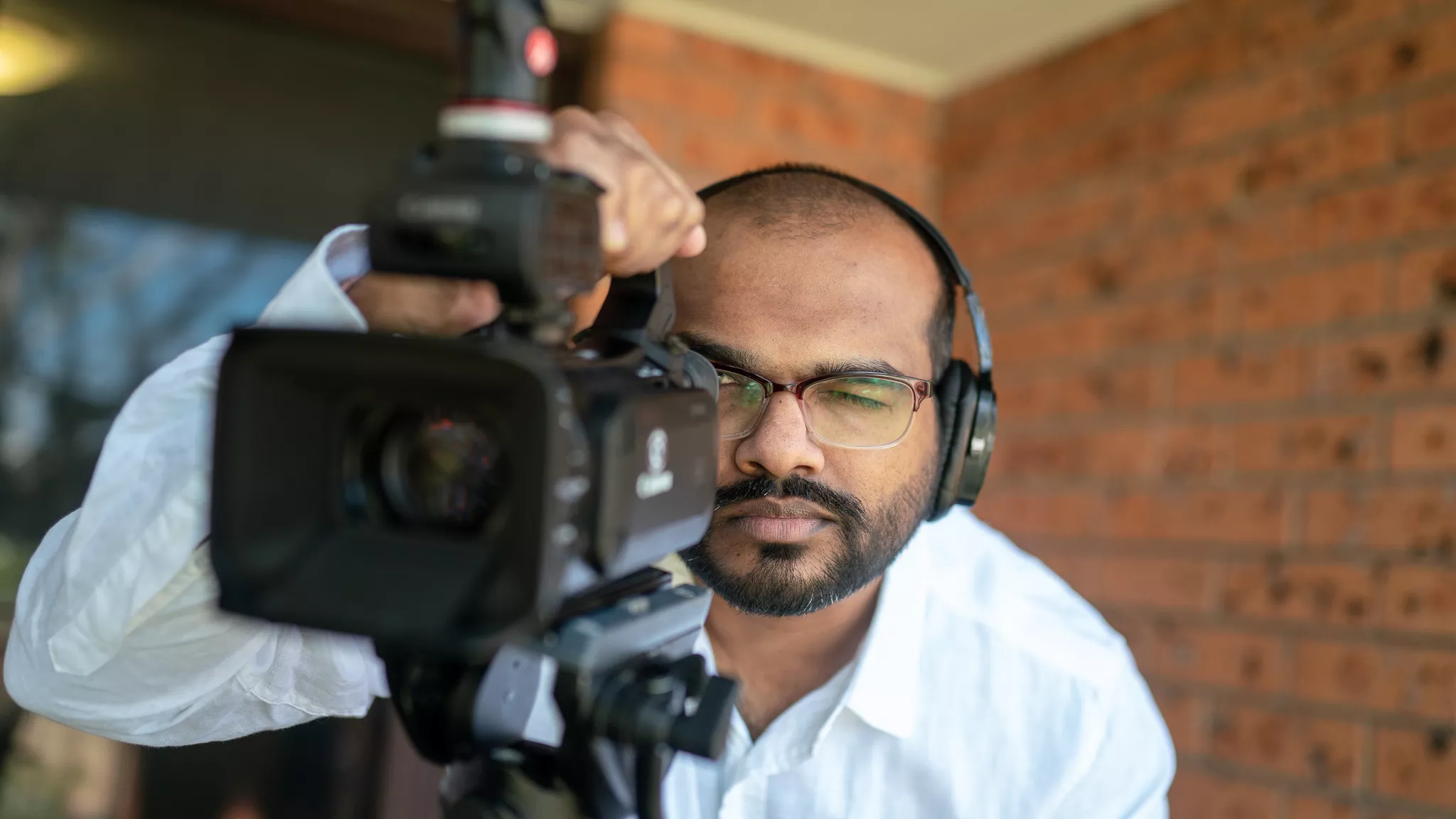 Videographer films with a professional camera and headphones on a commercial videography shoot