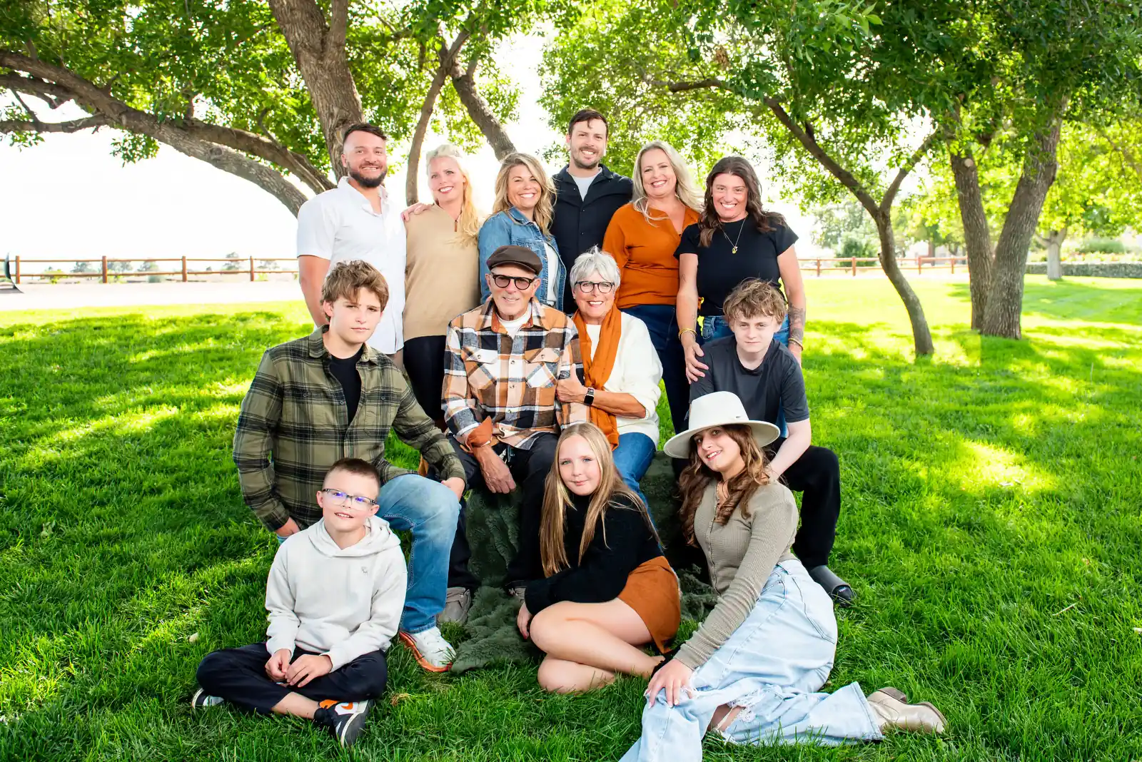 Large family photo ideas: three generations arranged in layers on a lawn under trees