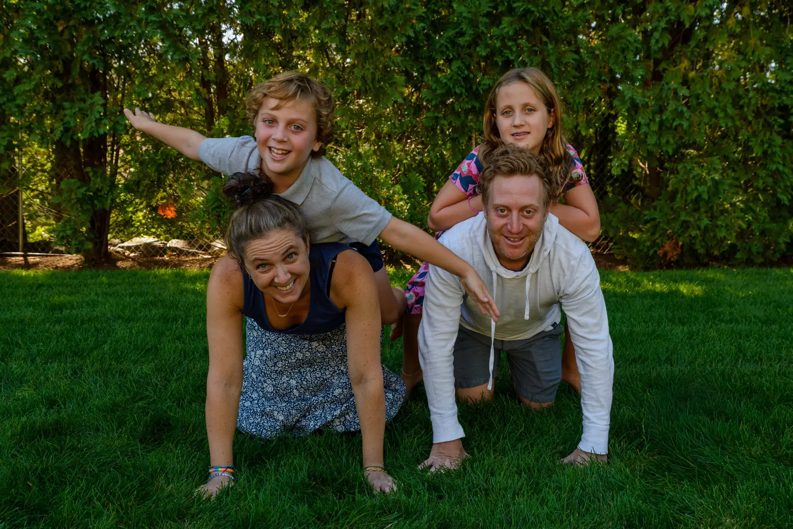 Outdoor family photo ideas: a family stacked into a human pyramid on the grass