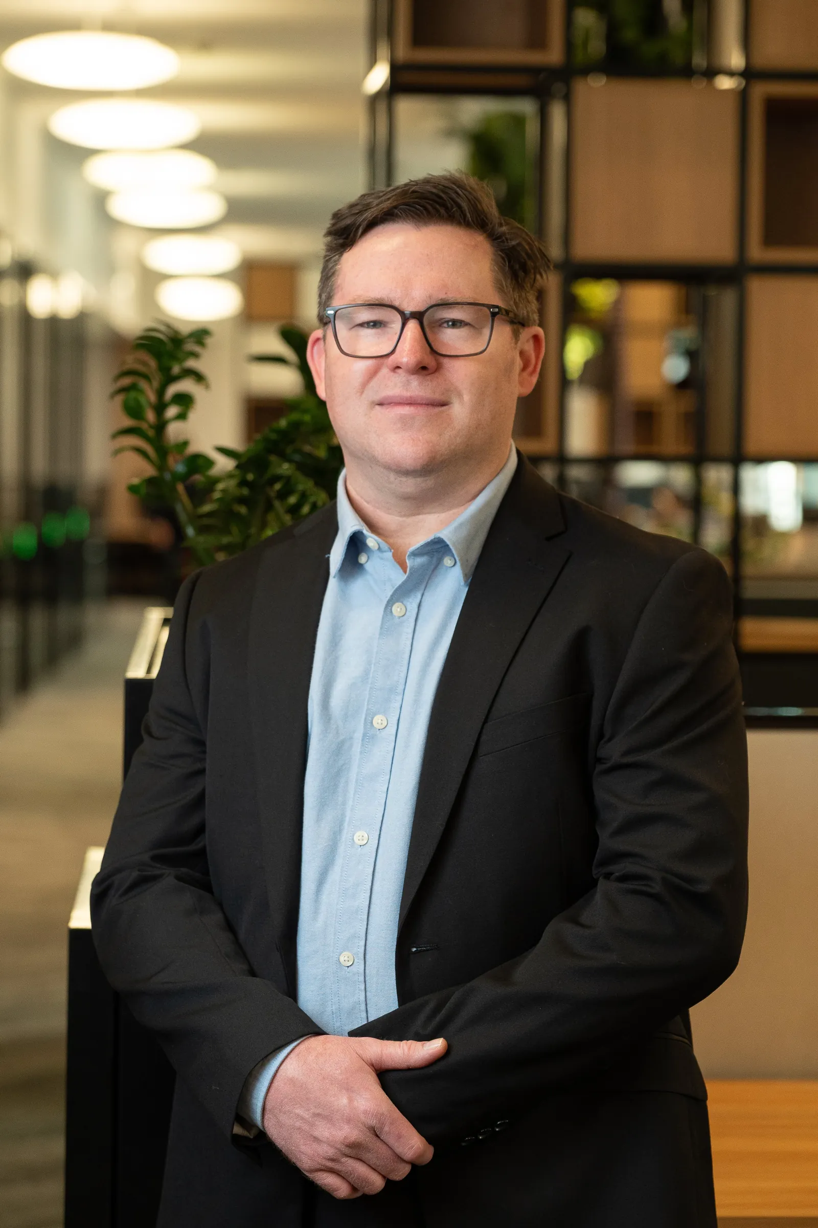 Environmental headshot examples: man in a blazer in an open-plan office, background blurred.