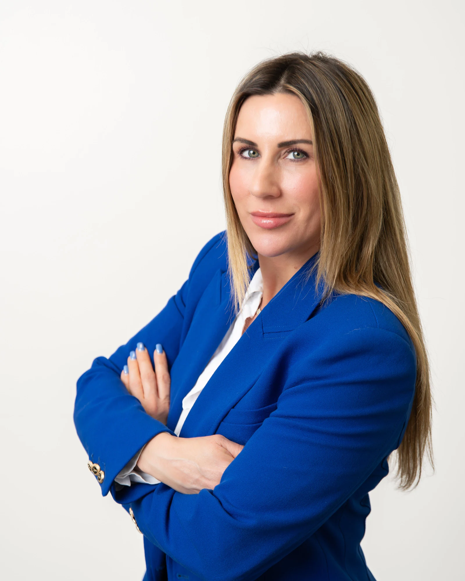 Professional headshot examples: waist-up crop of a woman in a blue blazer with arms folded.