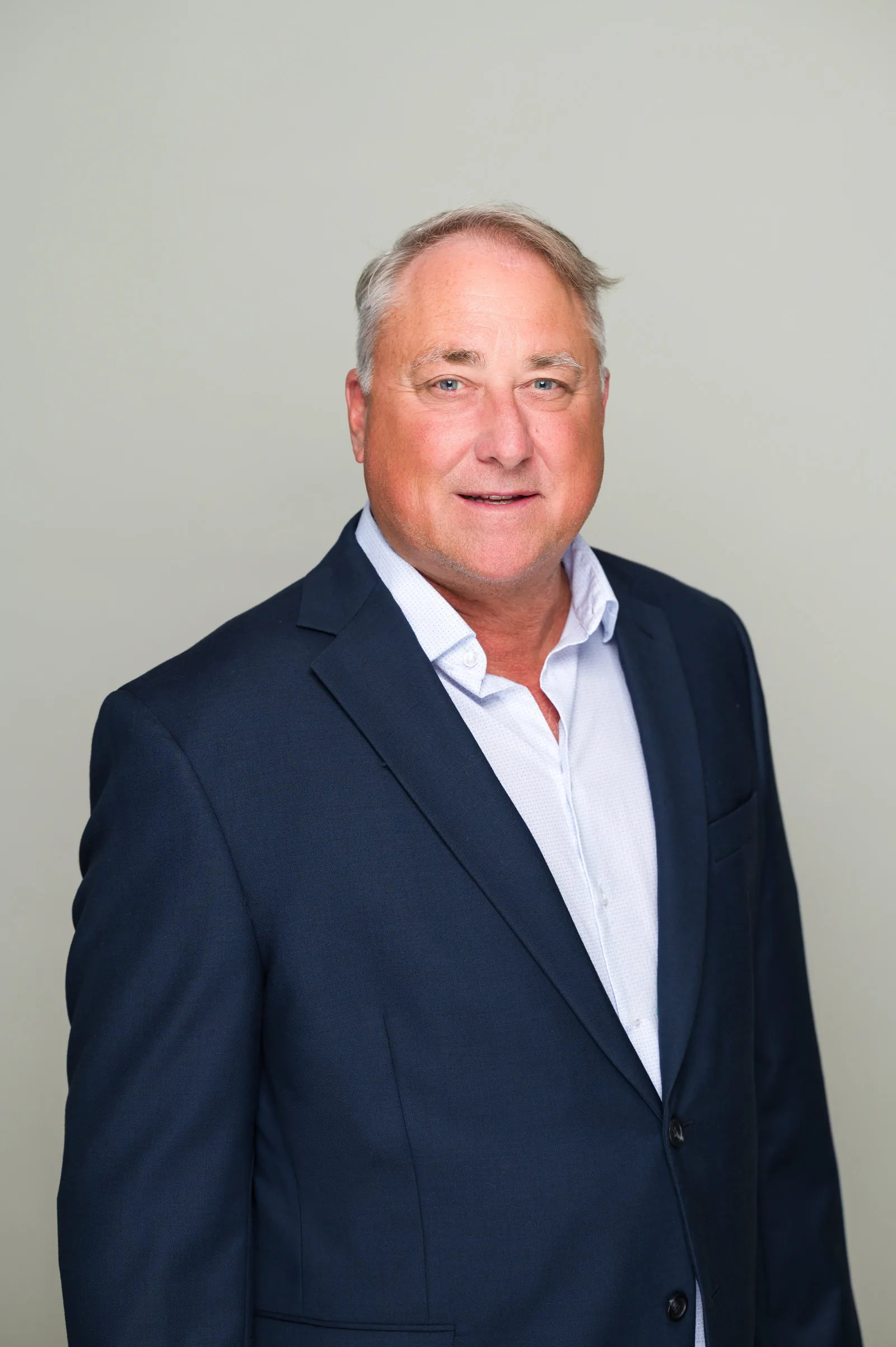 Corporate headshot examples: man in a navy suit on a plain light-gray backdrop.