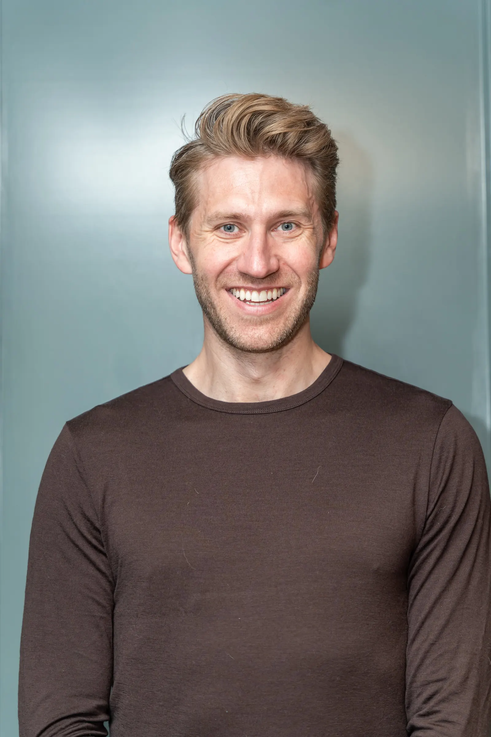 Headshot examples with a colored background: man in a brown sweater on a teal backdrop.